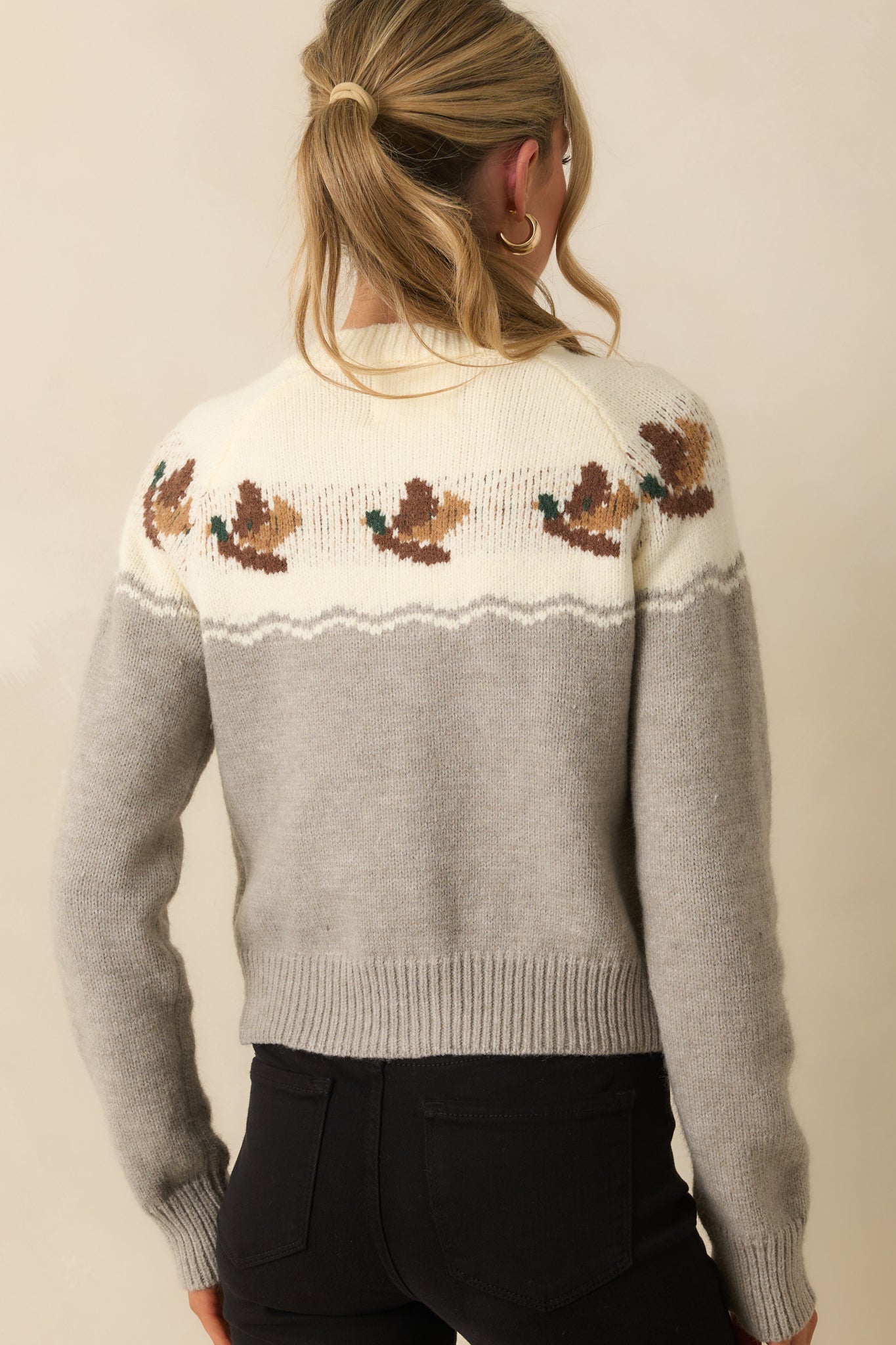Rear view of the cardigan showing the intarsia duck motif across the upper back and ribbed hem.
