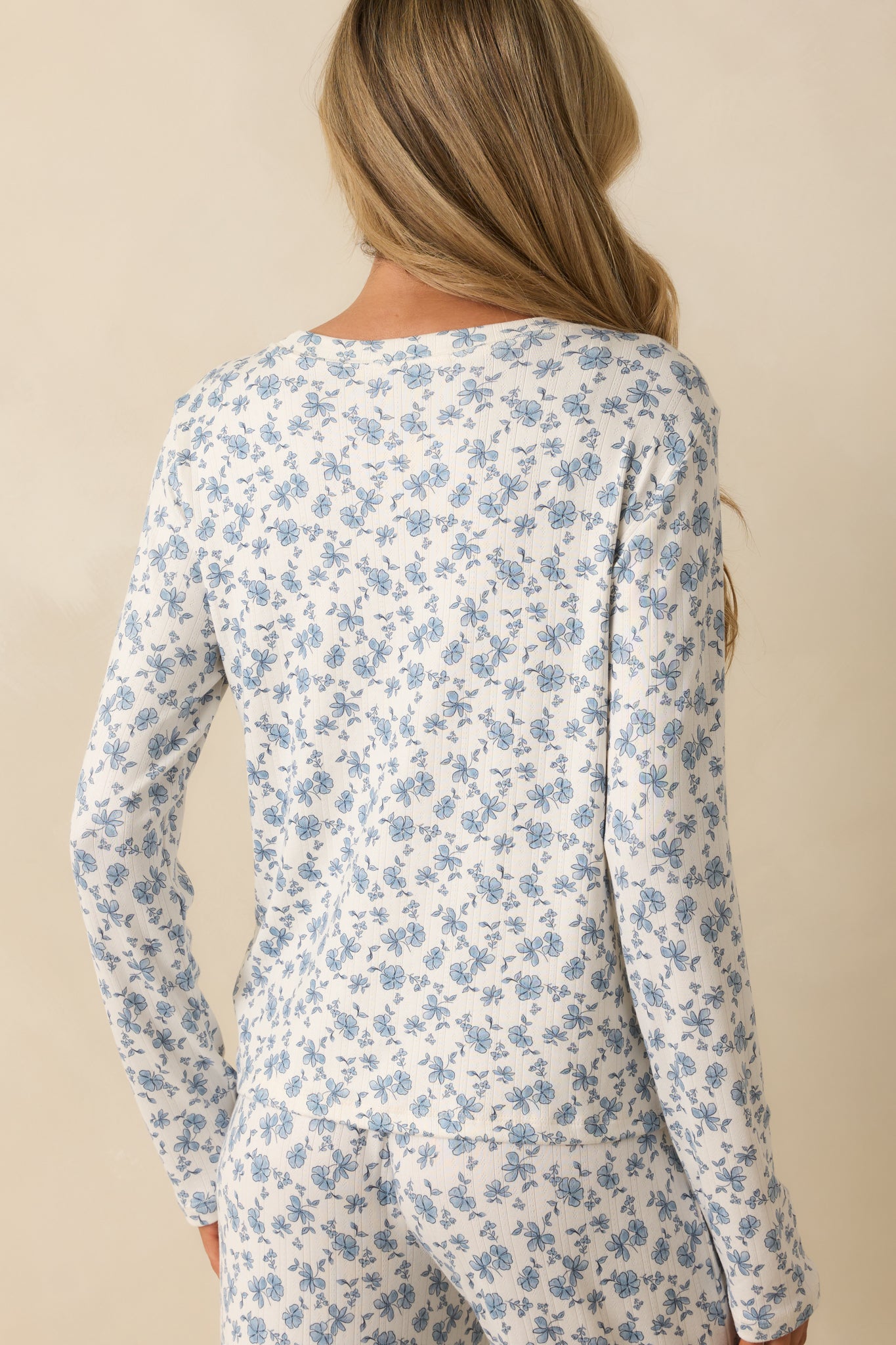 Rear view of the ivory and blue floral top with long sleeves and relaxed fit.