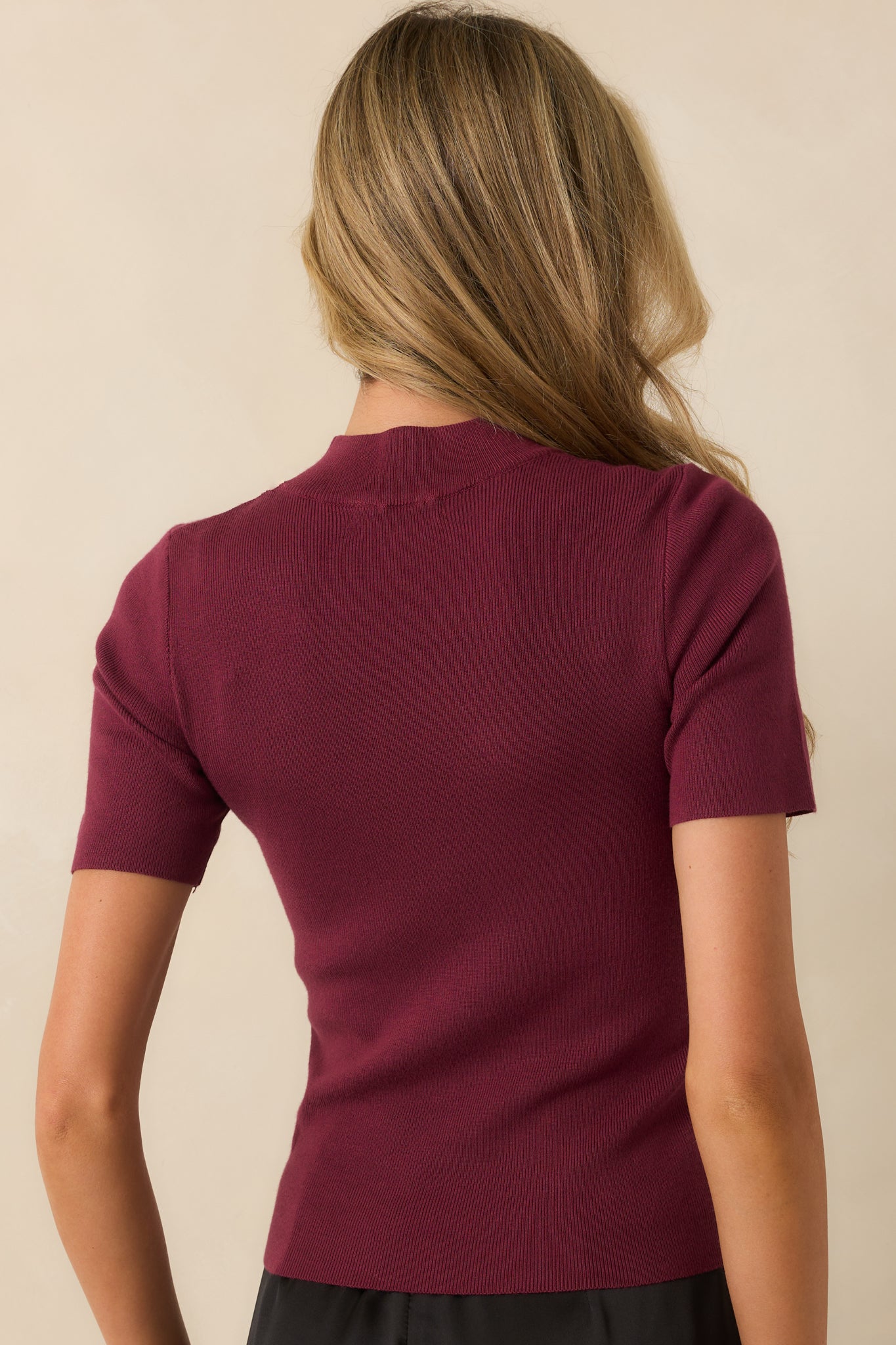 A back view of the wine red ribbed top highlighting its fitted cut and short sleeves.
