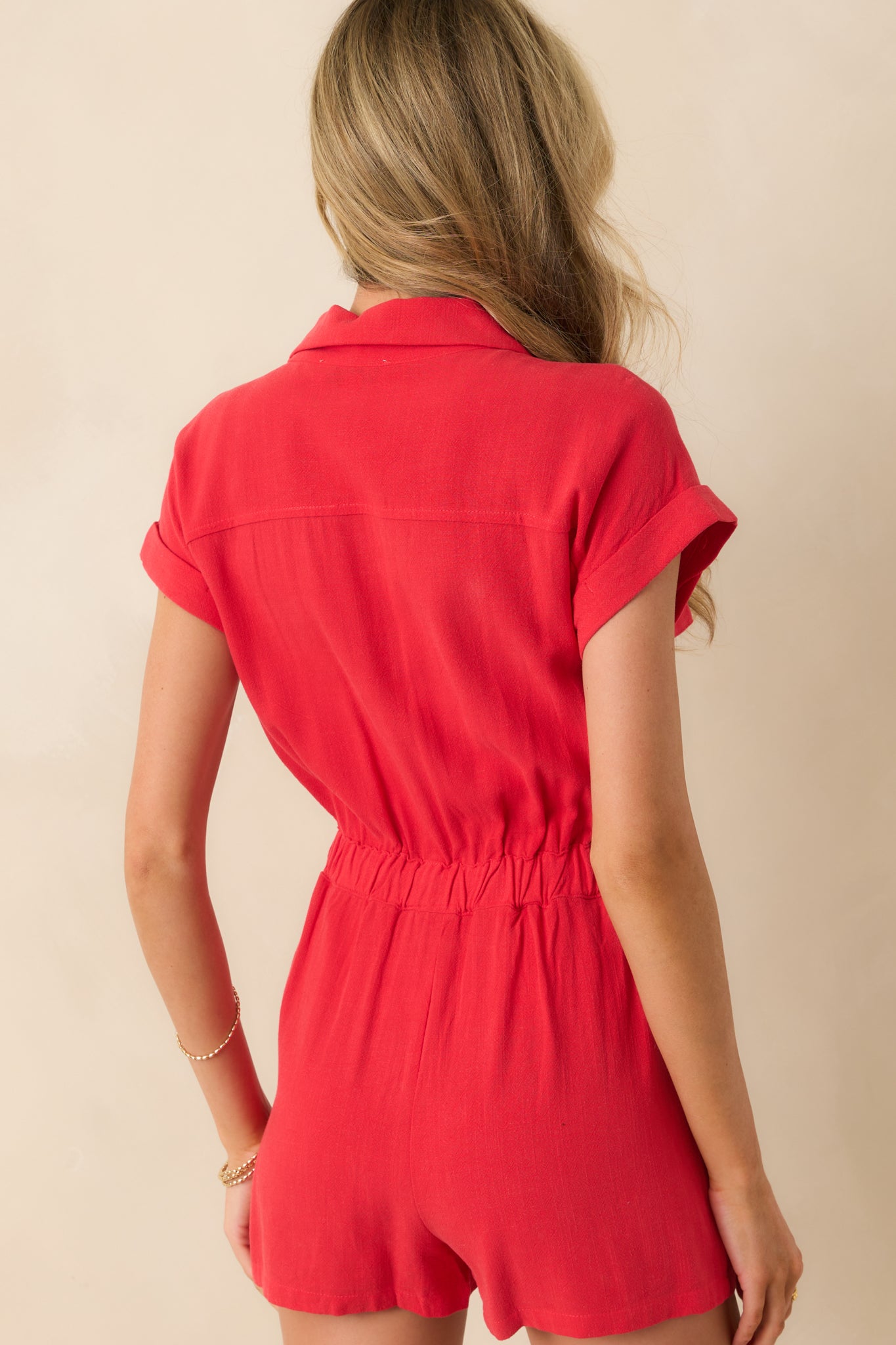 A back view of the romper showing its elastic waistband, cuffed sleeves, and back seam details.