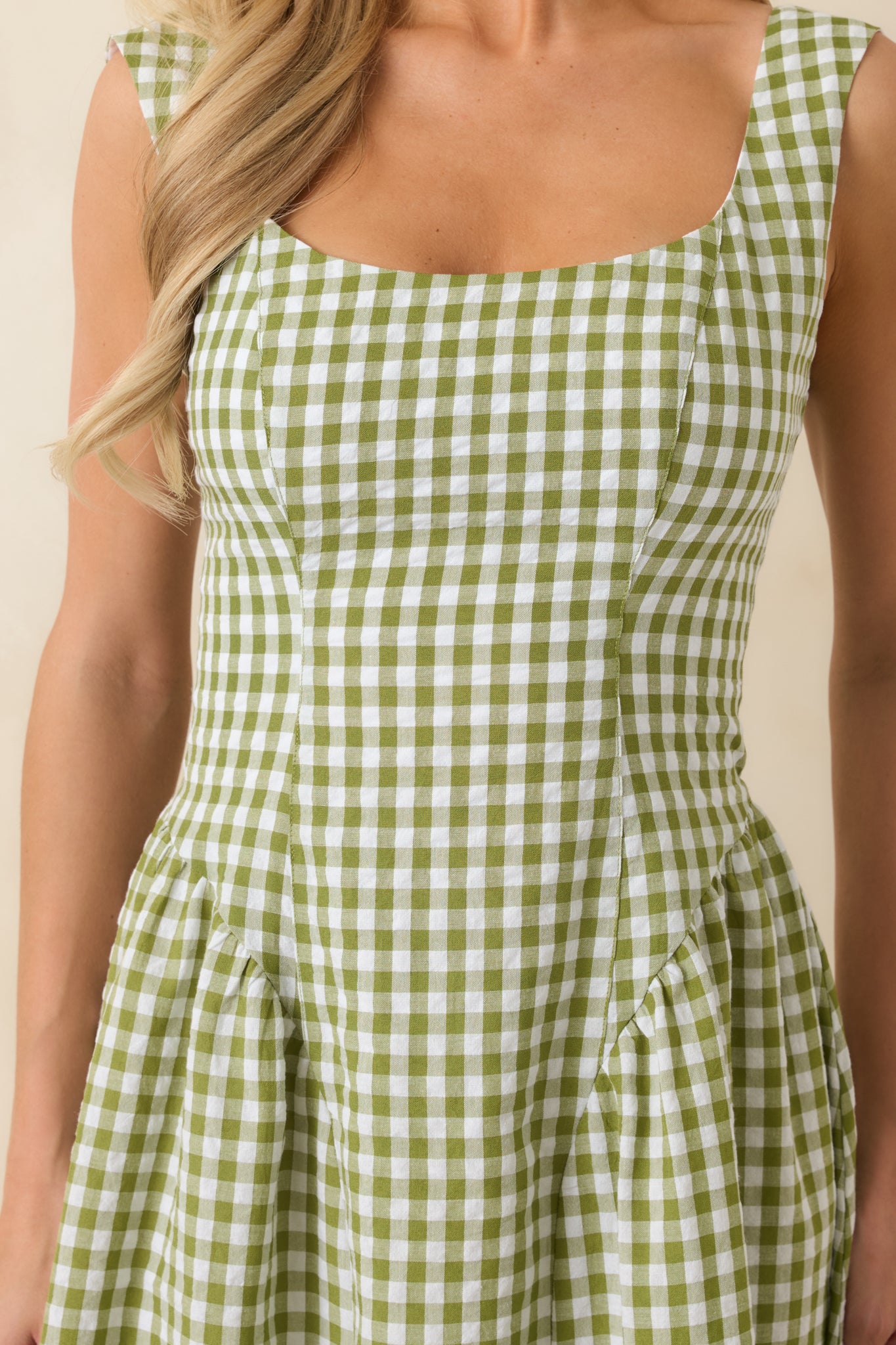 Detailed view of green and white gingham fabric with structured texture, square neckline, and wide strap construction.