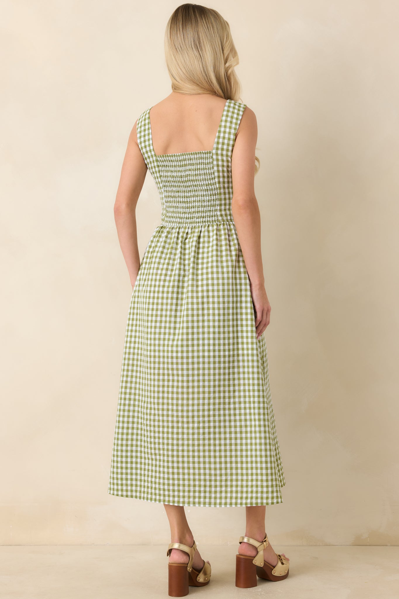 Rear view of green gingham midi dress highlighting smocked back panel, wide straps, and full flowing skirt.