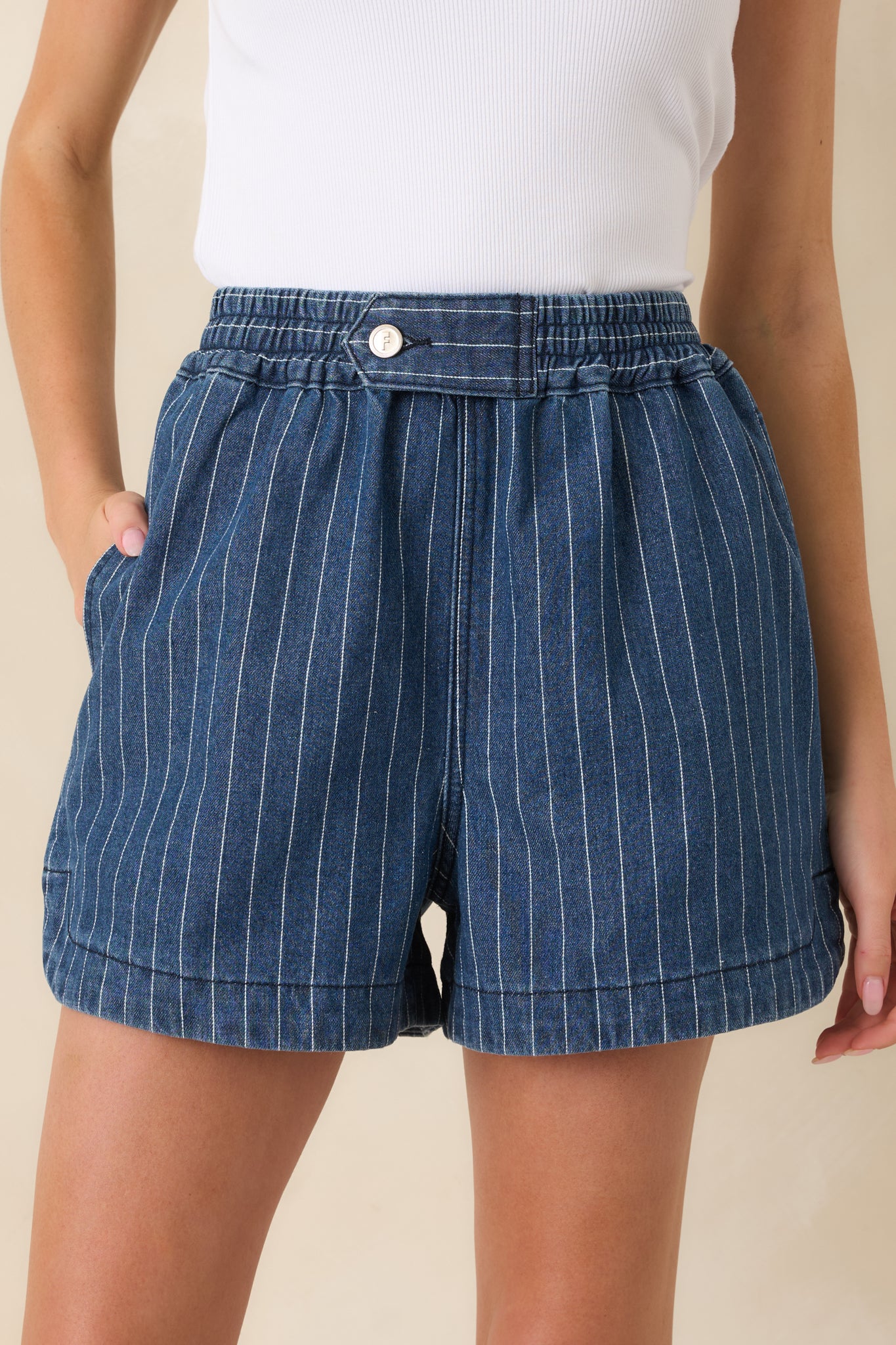 Close-up of cotton denim shorts showing stitching, utility tab construction, and fabric texture.