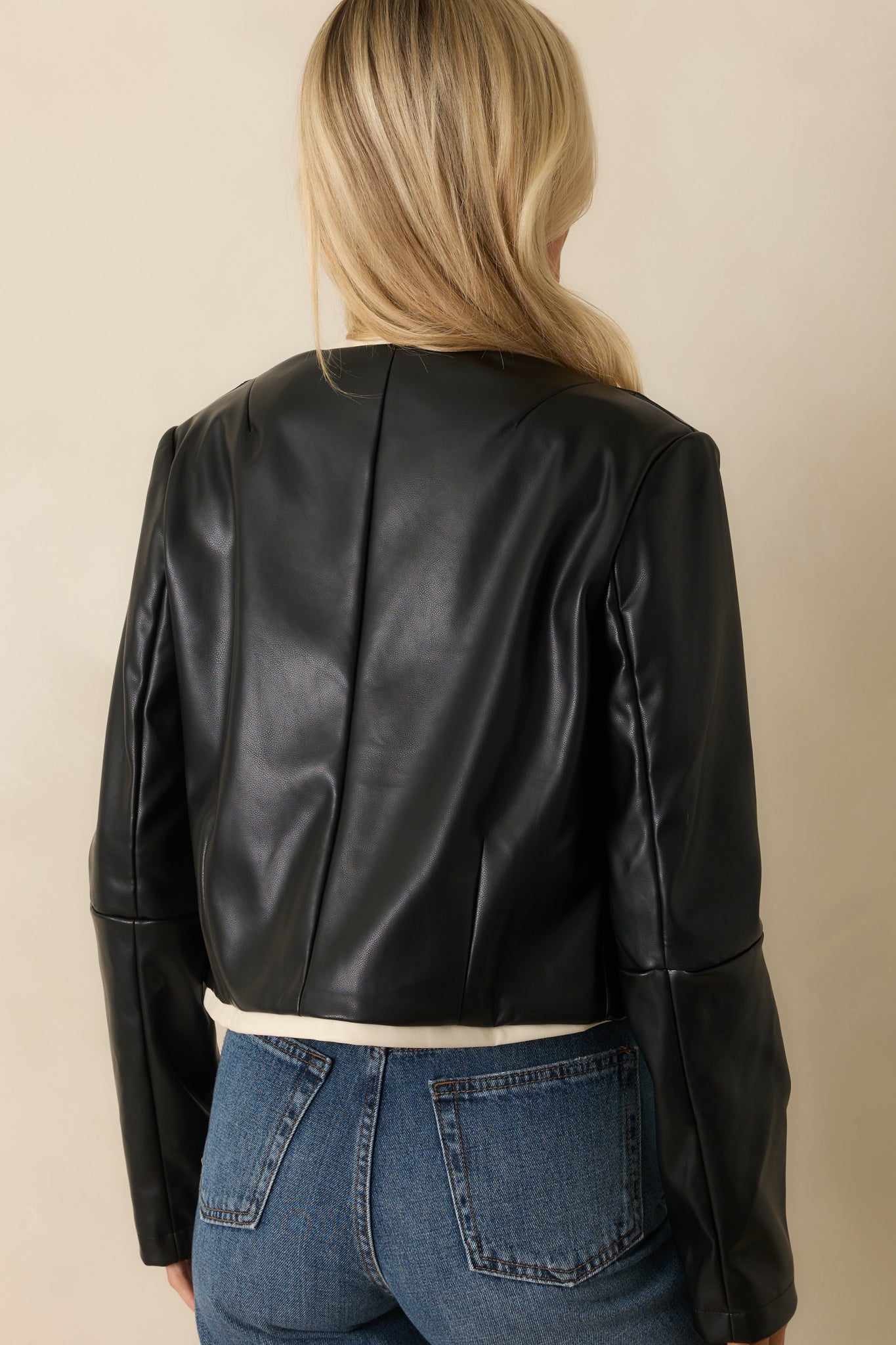 Rear view of the black jacket highlighting the smooth structure and ivory trim outlining the edges.