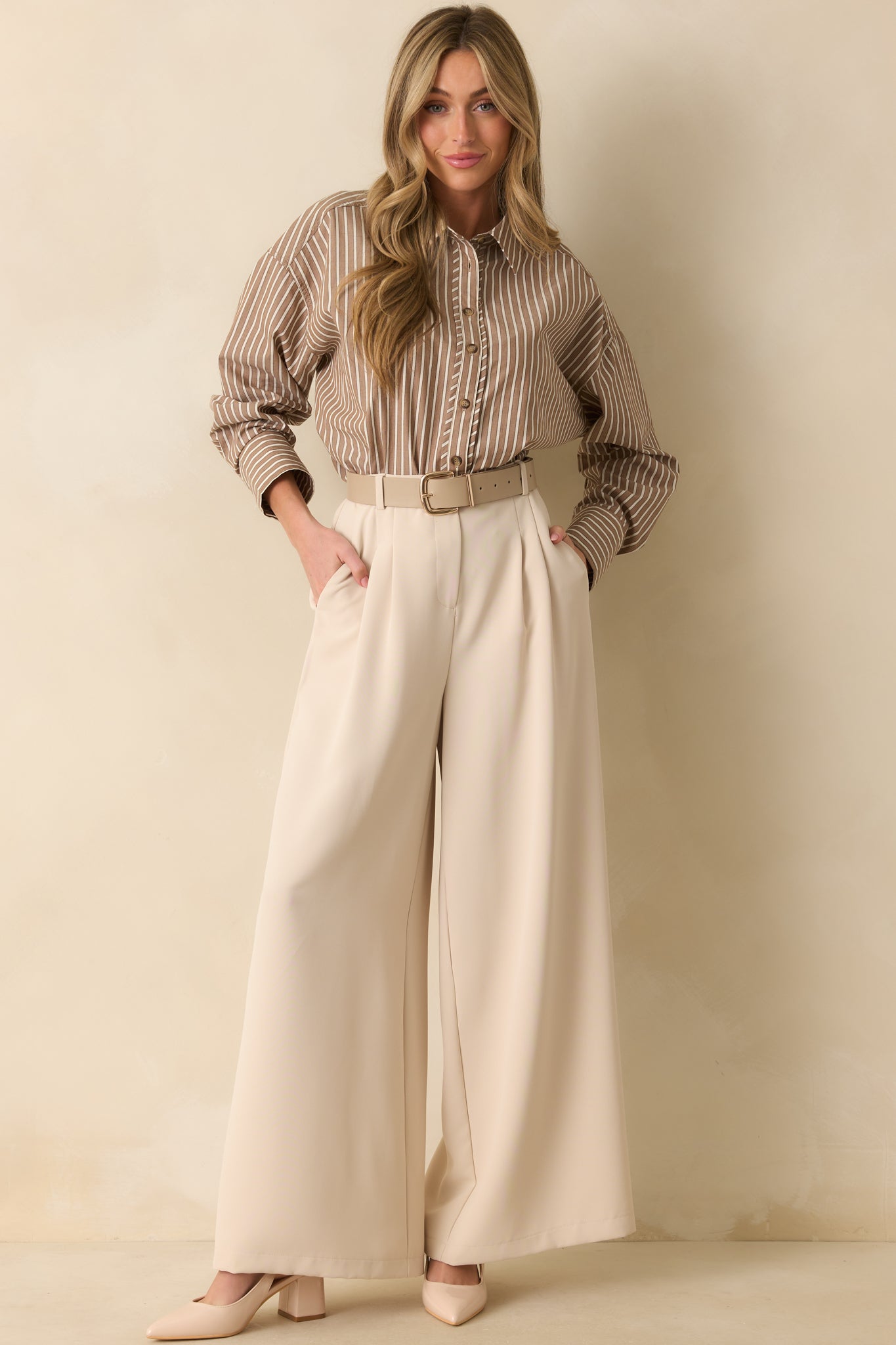 Taupe trousers featuring functional belt loops, an elastic waist insert, and hip pockets.