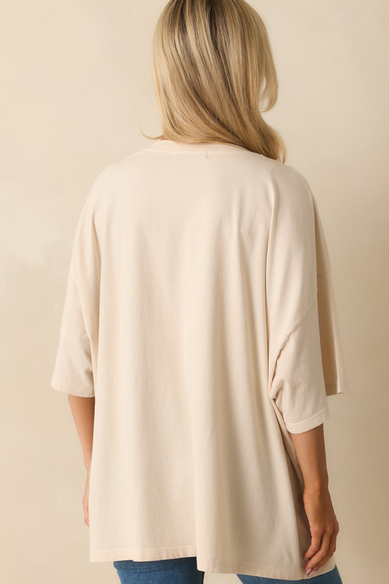 Rear view of the ivory tee showing a plain back with short sleeves and oversized fit.