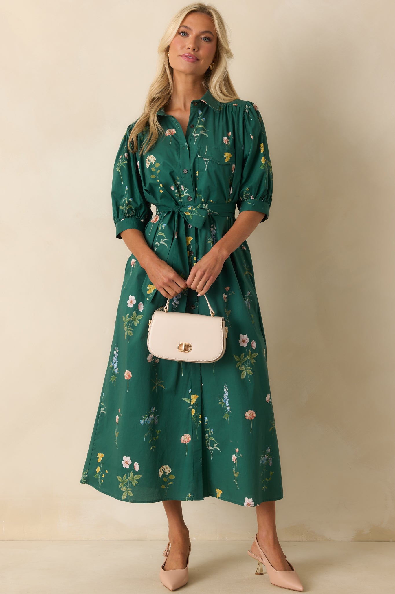 Forest green maxi dress with multicolor floral print, half-length puff sleeves, and a relaxed silhouette with functional pockets and optional belt.