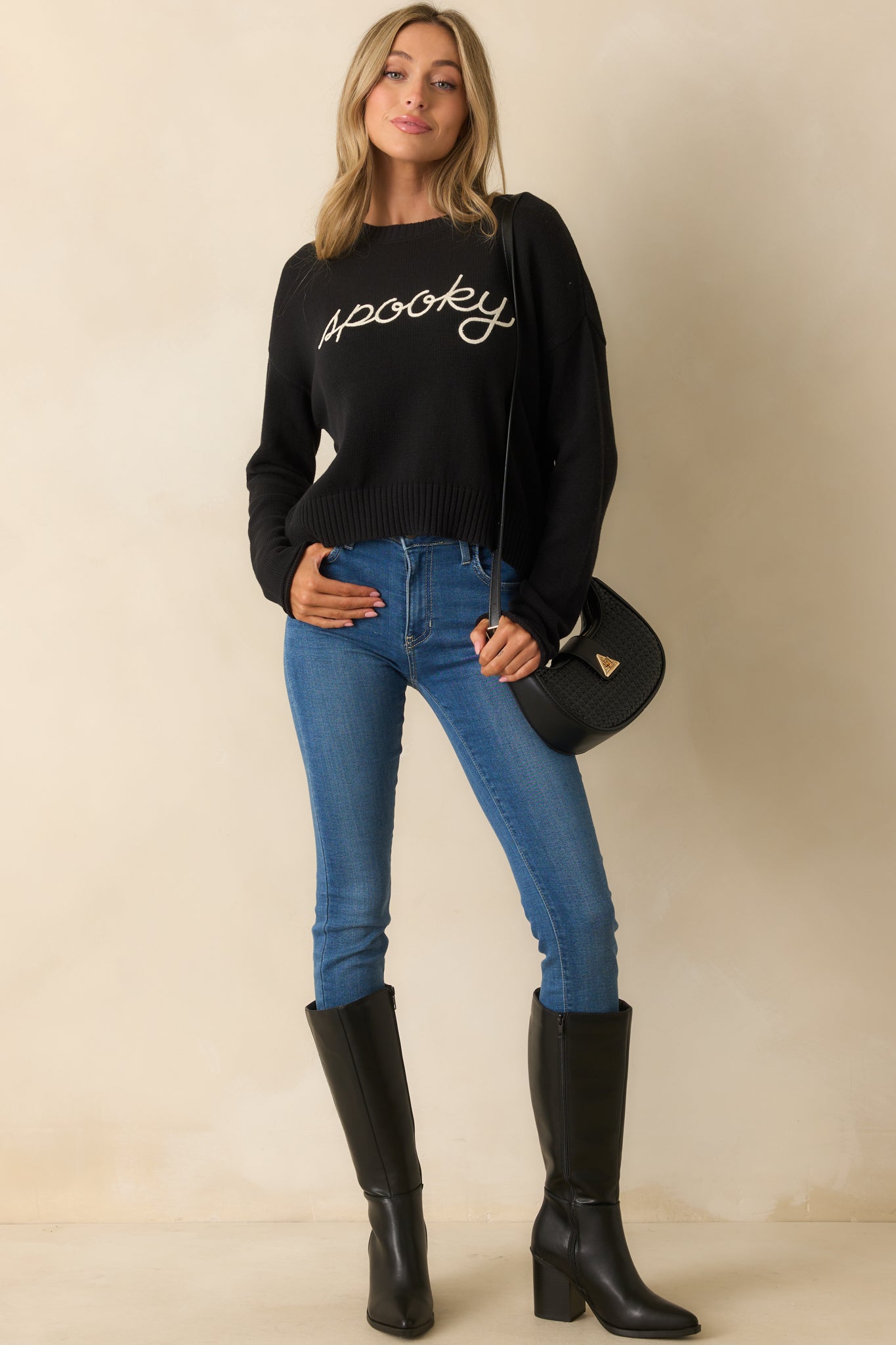 Full view of the knit sweater showing its playful “spooky” embroidery detail
