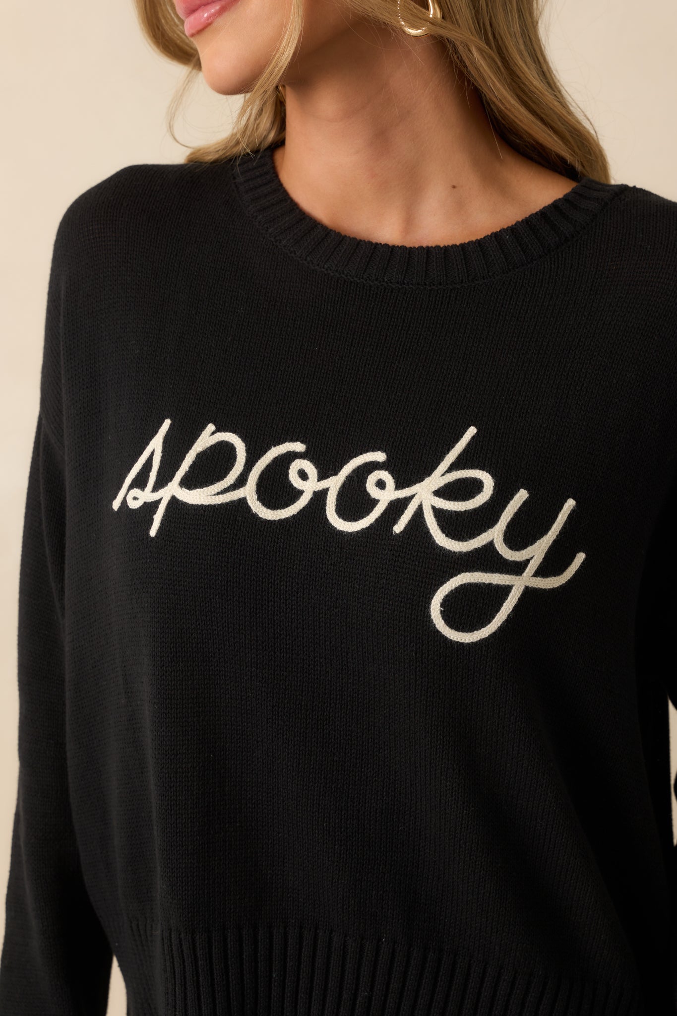 Embroidered ivory “spooky” script stitched into the black cotton knit.