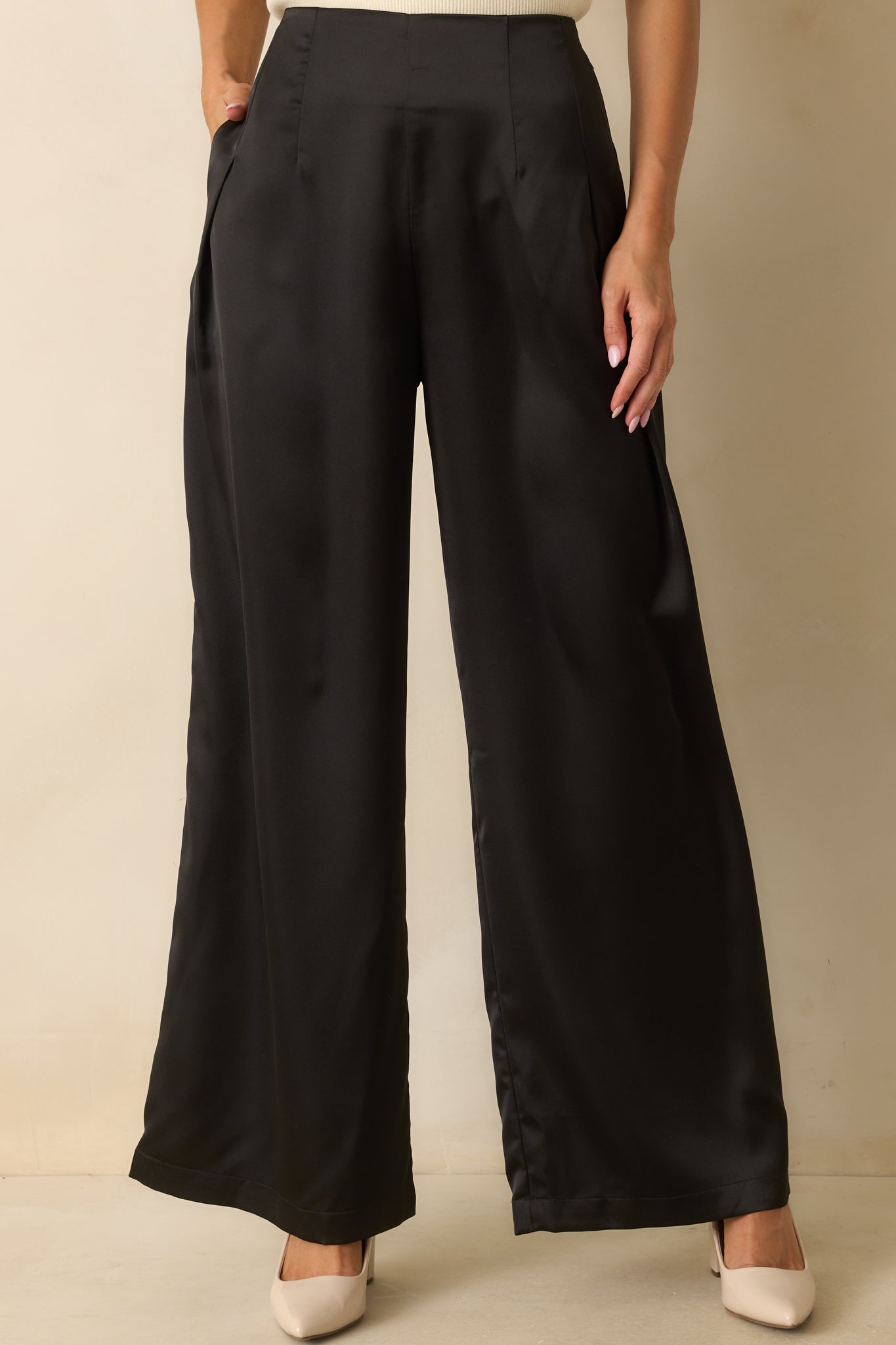 Detail of the satin fabric and smooth front of the black wide-leg pants.