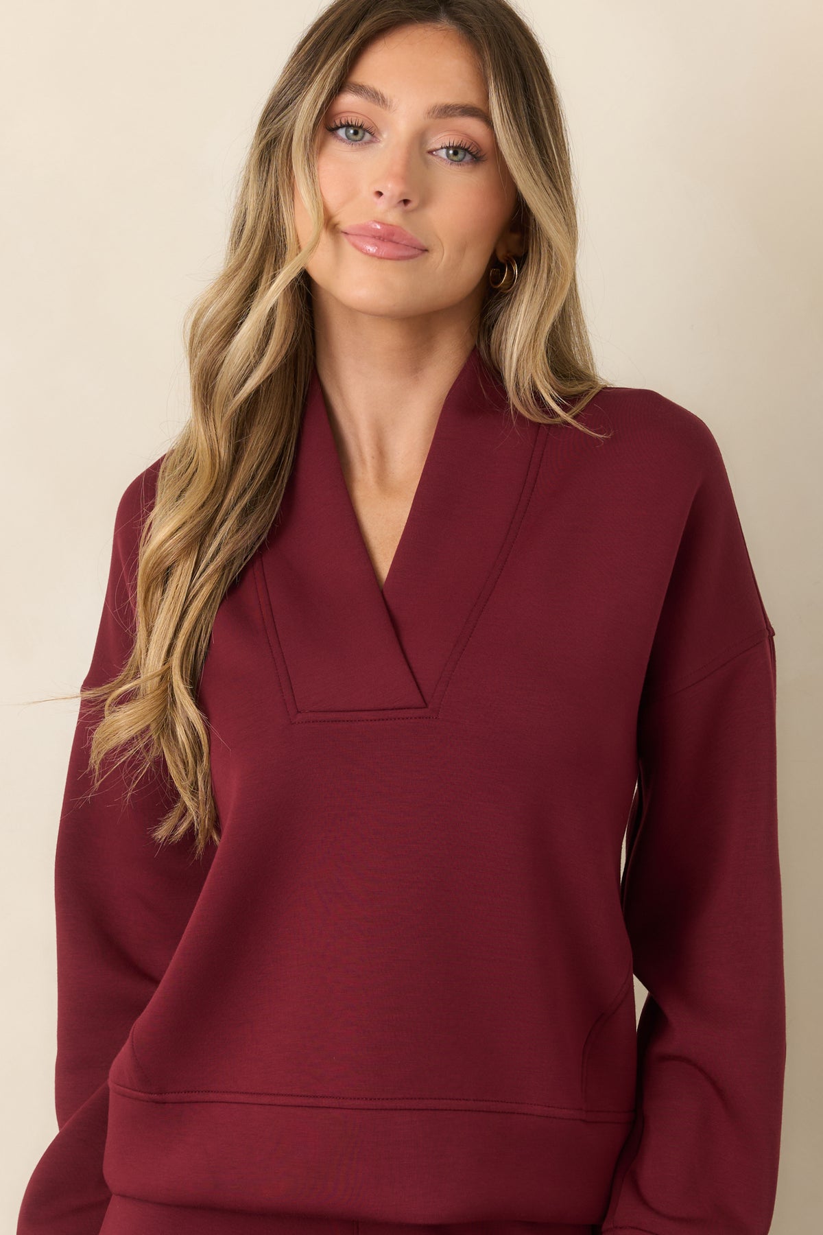 Close-up of vino red sweatshirt with structured V-neckline, wide collar, and smooth finish