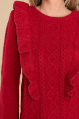 Close up view of this sweater that features ruffles around the bust and a cable knit detail on the front.
