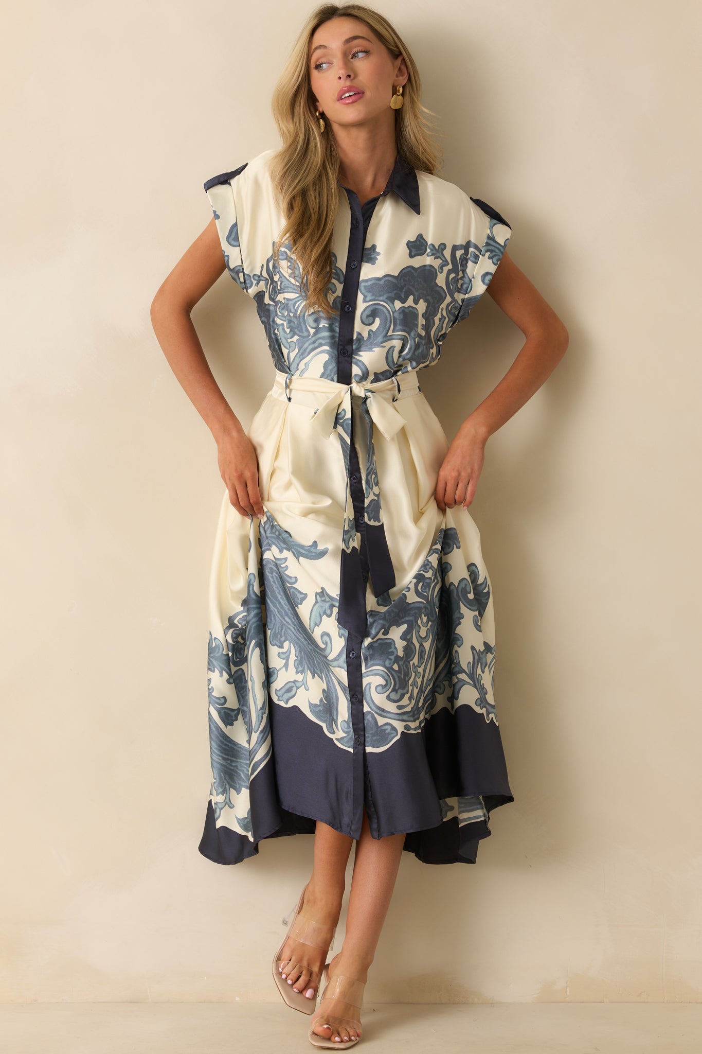 Ivory maxi dress with navy baroque-inspired border print, collared neckline, cuffed short sleeves, and flowing hem.