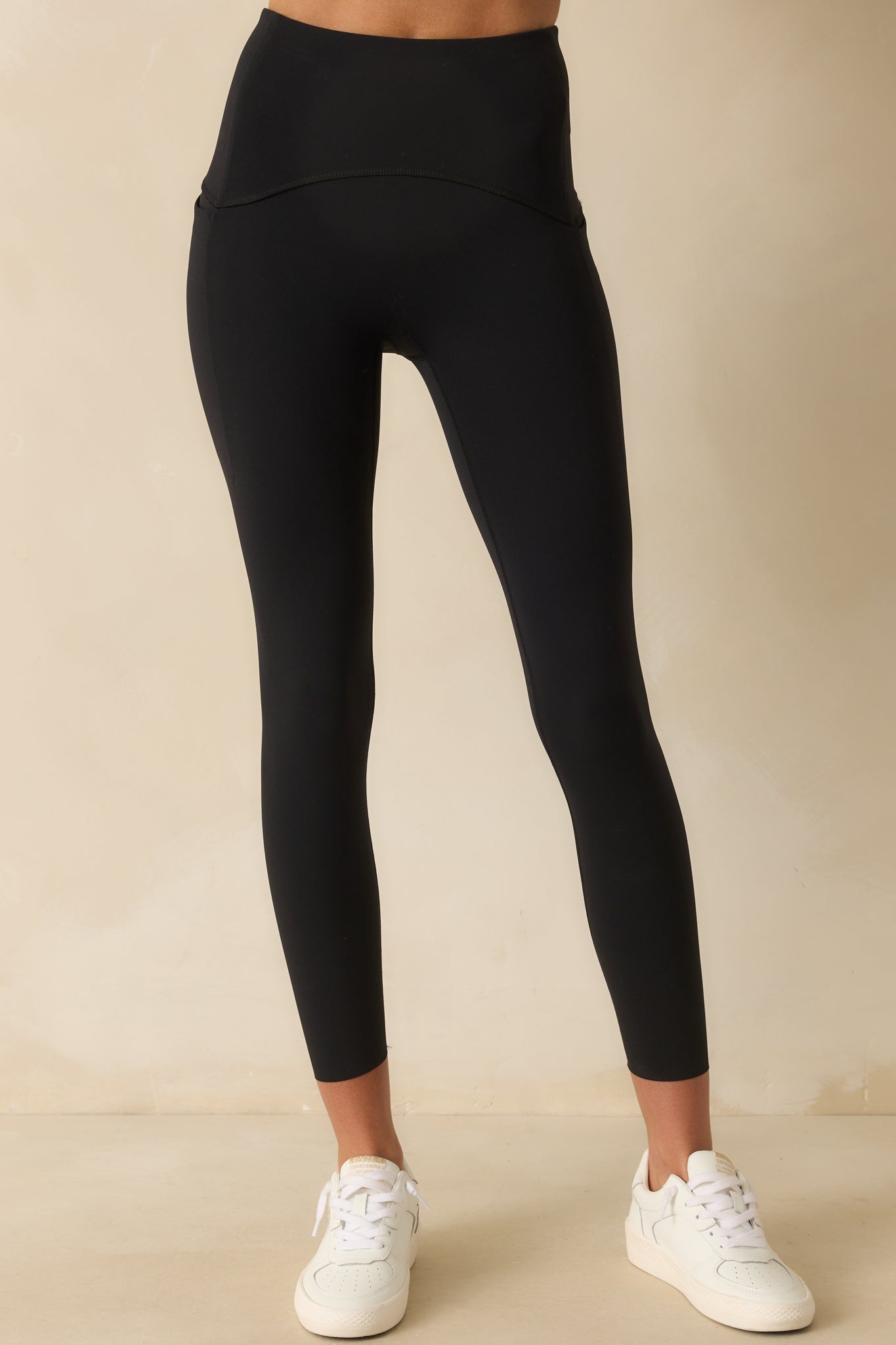 A cropped front view focusing on the waistband design of the black leggings.