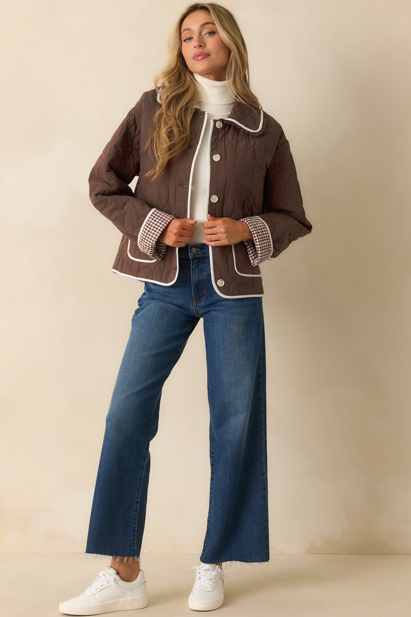 Quilted brown jacket with collared neckline, patch pockets, and contrasting floral stitching details throughout.