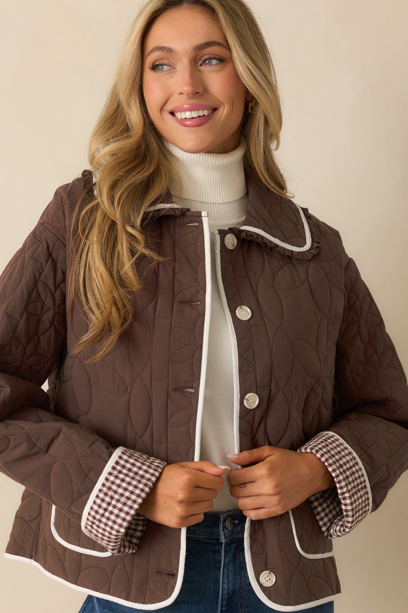 Close view of the collared neckline with ruffle trim and floral quilt stitching on the brown jacket.