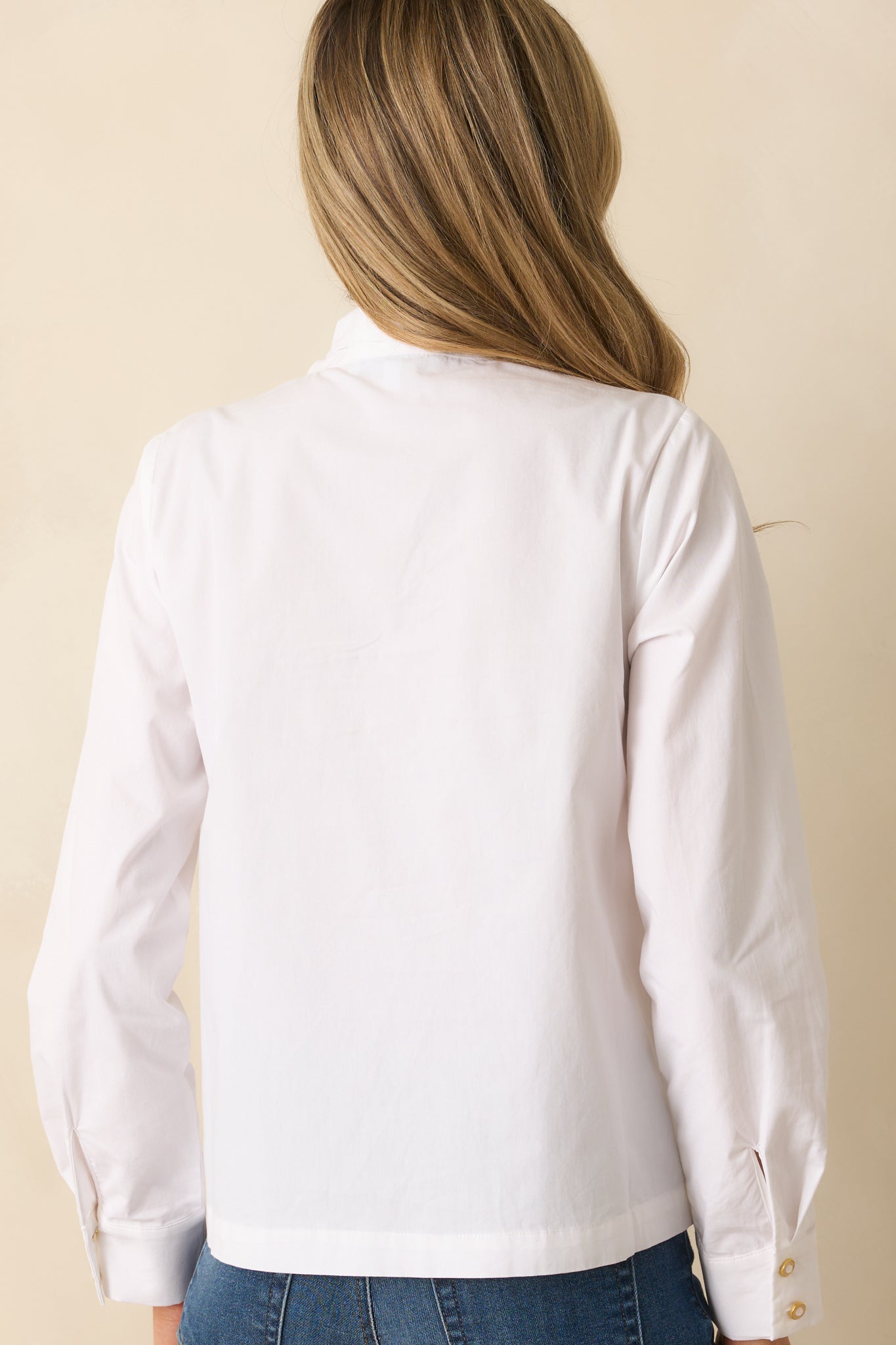 Back view of the top, showing the long sleeves and relaxed fit of the white button-front blouse.