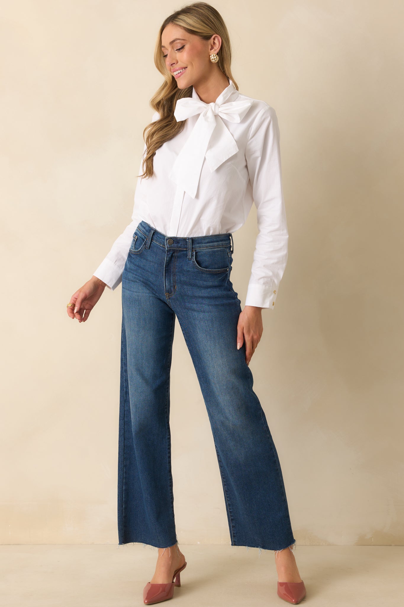 Front-facing full body view of a white long sleeve top with a self-tie bow neckline, button front closure, and relaxed fit.
