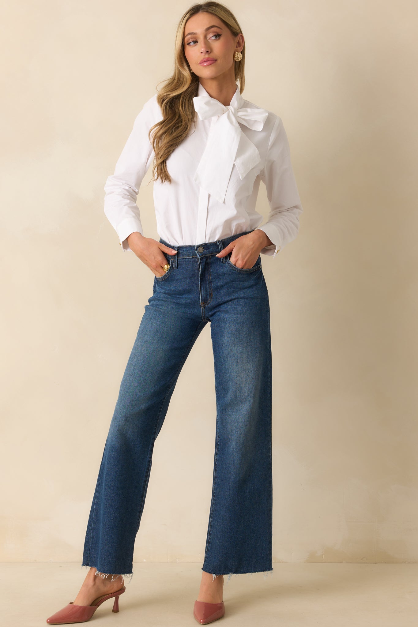 Full body shot showing the white top with long sleeves, functional button cuffs, and a loose silhouette.