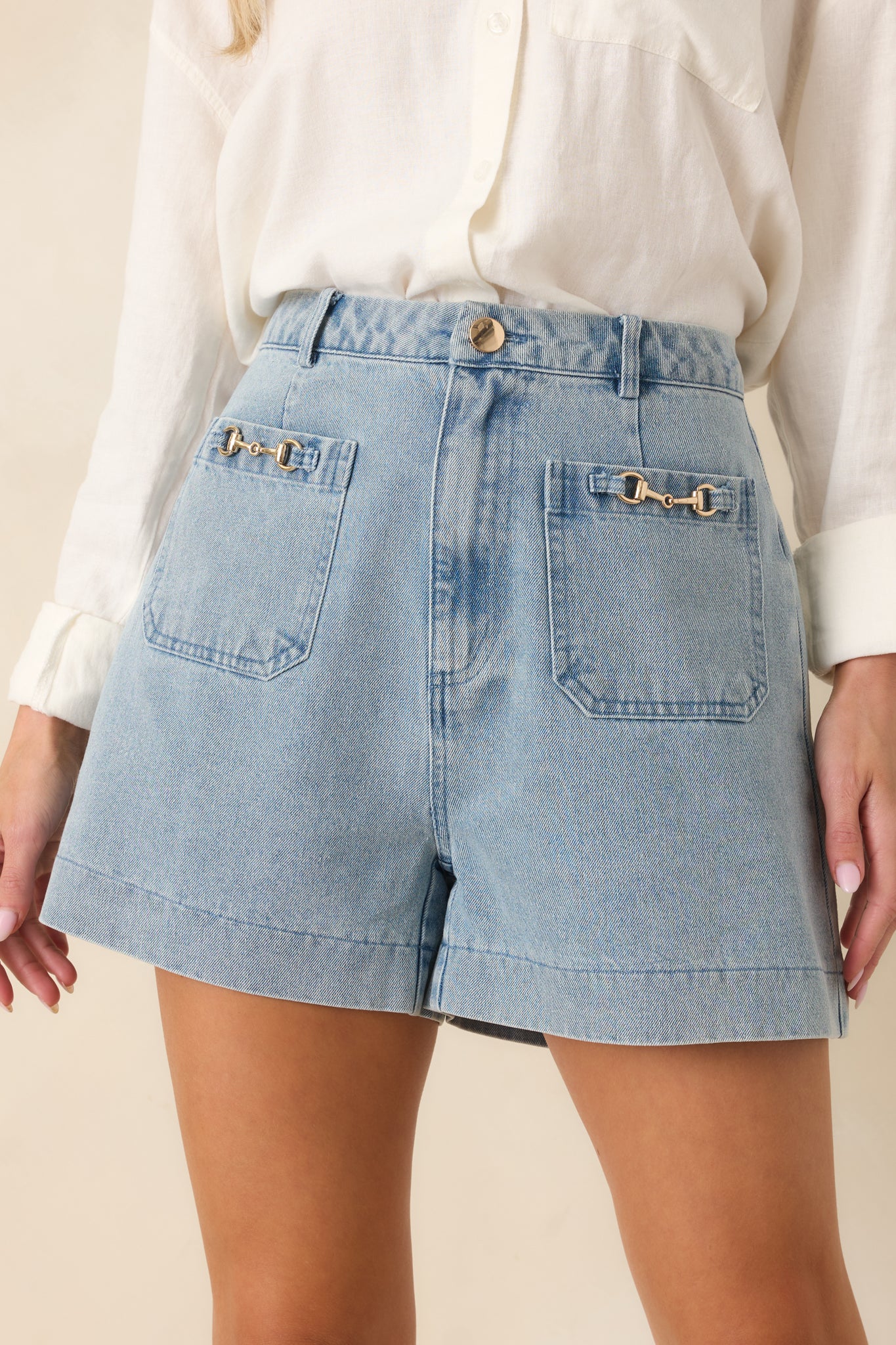 Detailed view of decorative hardware on back pockets and light wash denim texture.