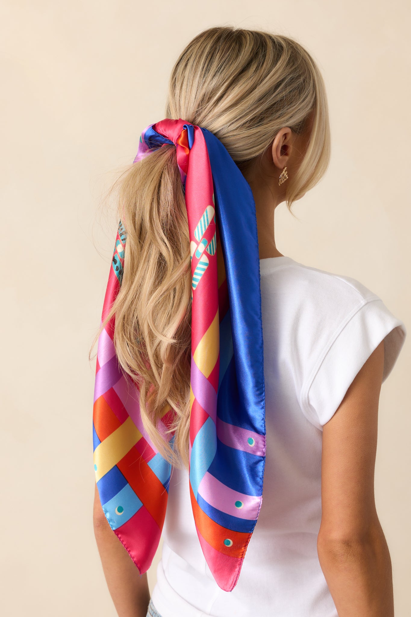 A fuchsia satin scarf with a bold multi-color chain print, accented by vibrant red, orange, yellow, green, and blue details along the corners and sides.