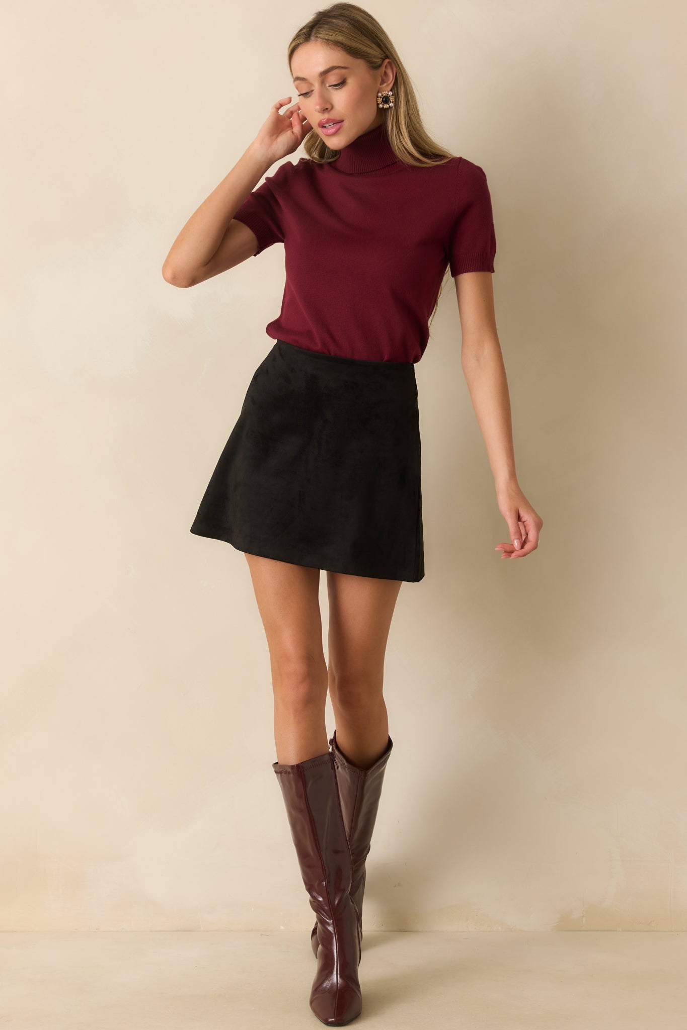 A-line black mini skirt in faux suede featuring a smooth, structured fabric and clean lines.