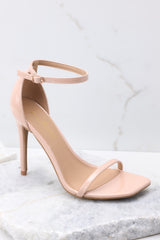 These all beige shoes feature an adjustable ankle strap, a thin strap over the foot, and a thin heel.
