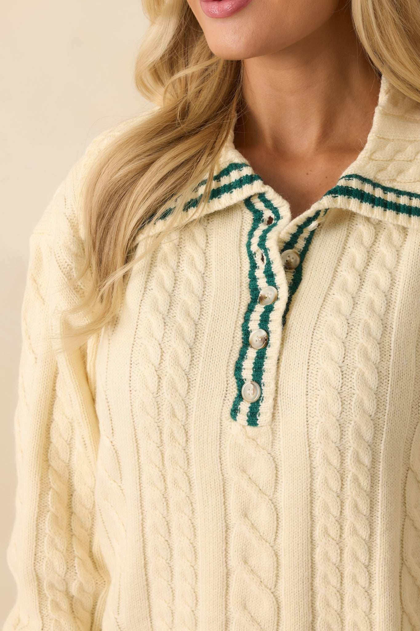 Soft acrylic-poly blend fabric with ivory cable knit texture, partial button placket, and green-trimmed collar.