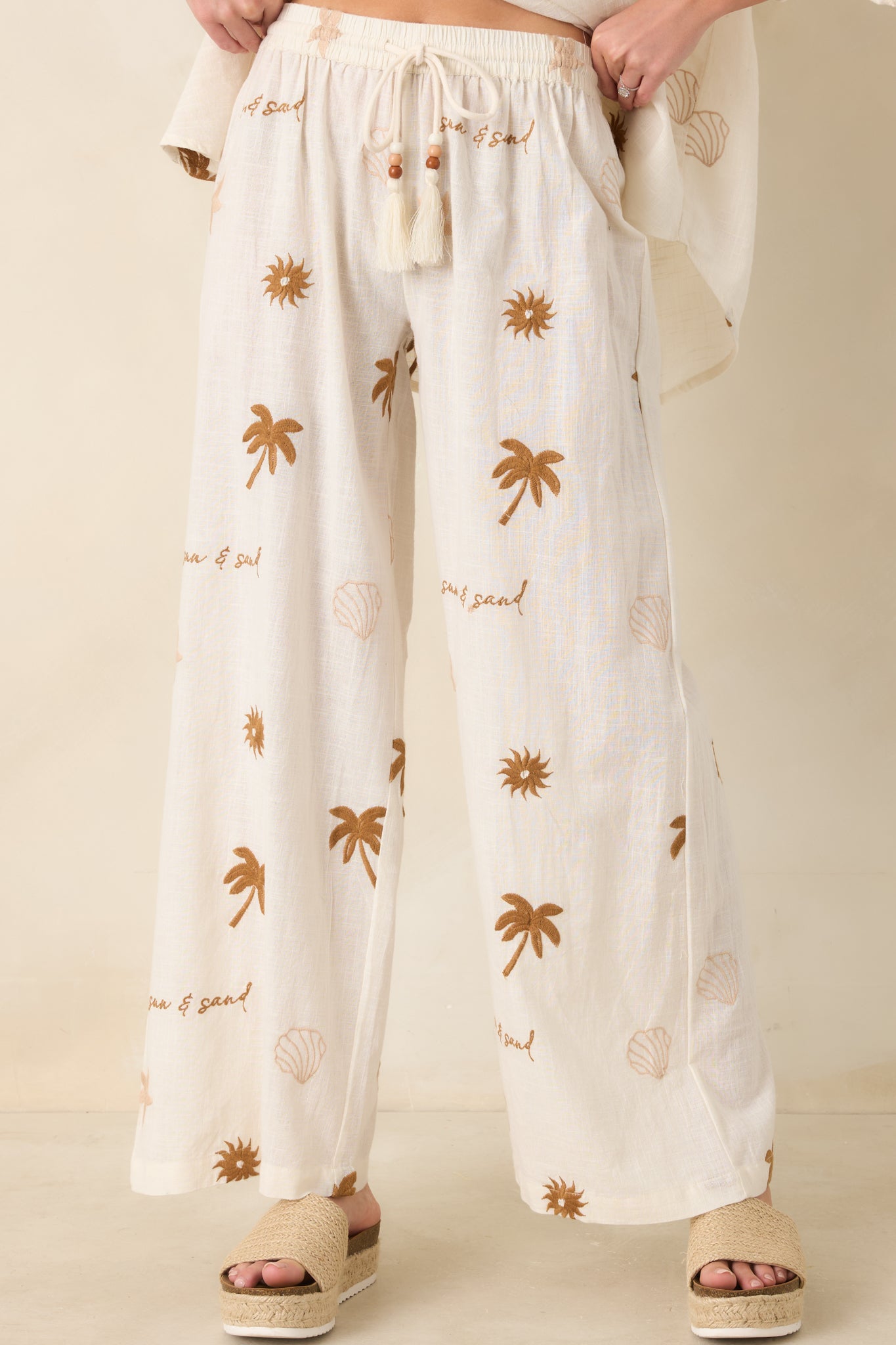 Adjustable drawstring detail with bead accents on light cotton pants.