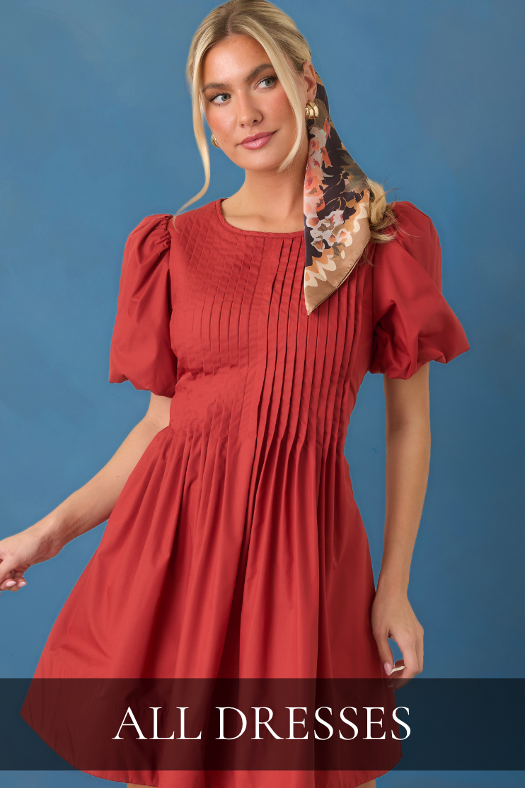 Model wearing rust colored mini dress. Text reads: "All Dresses."