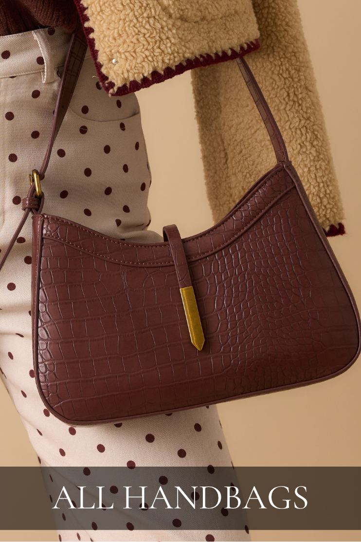 Model holding brown leather handbag. All Handbags.