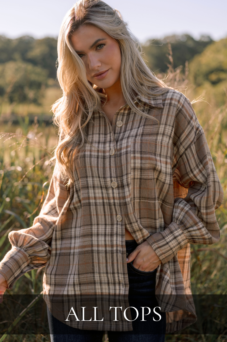 Model wearing a plaid button up with jeans. Text reads: "All Tops."