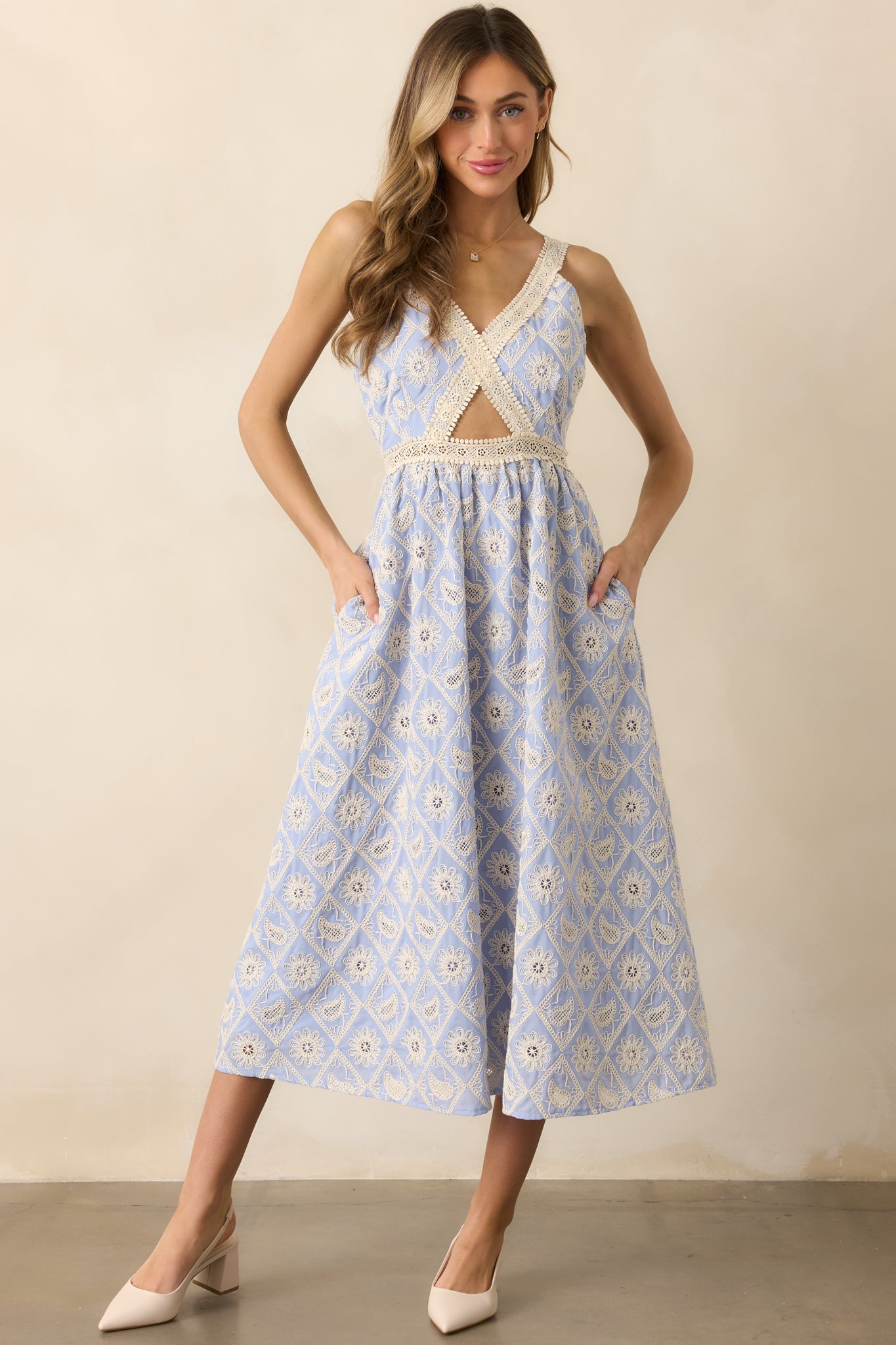 An eye-catching periwinkle dress with lace embroidery, a v-neckline, and a cutout in the bodice, offering adjustable straps that create a flattering and flexible fit.