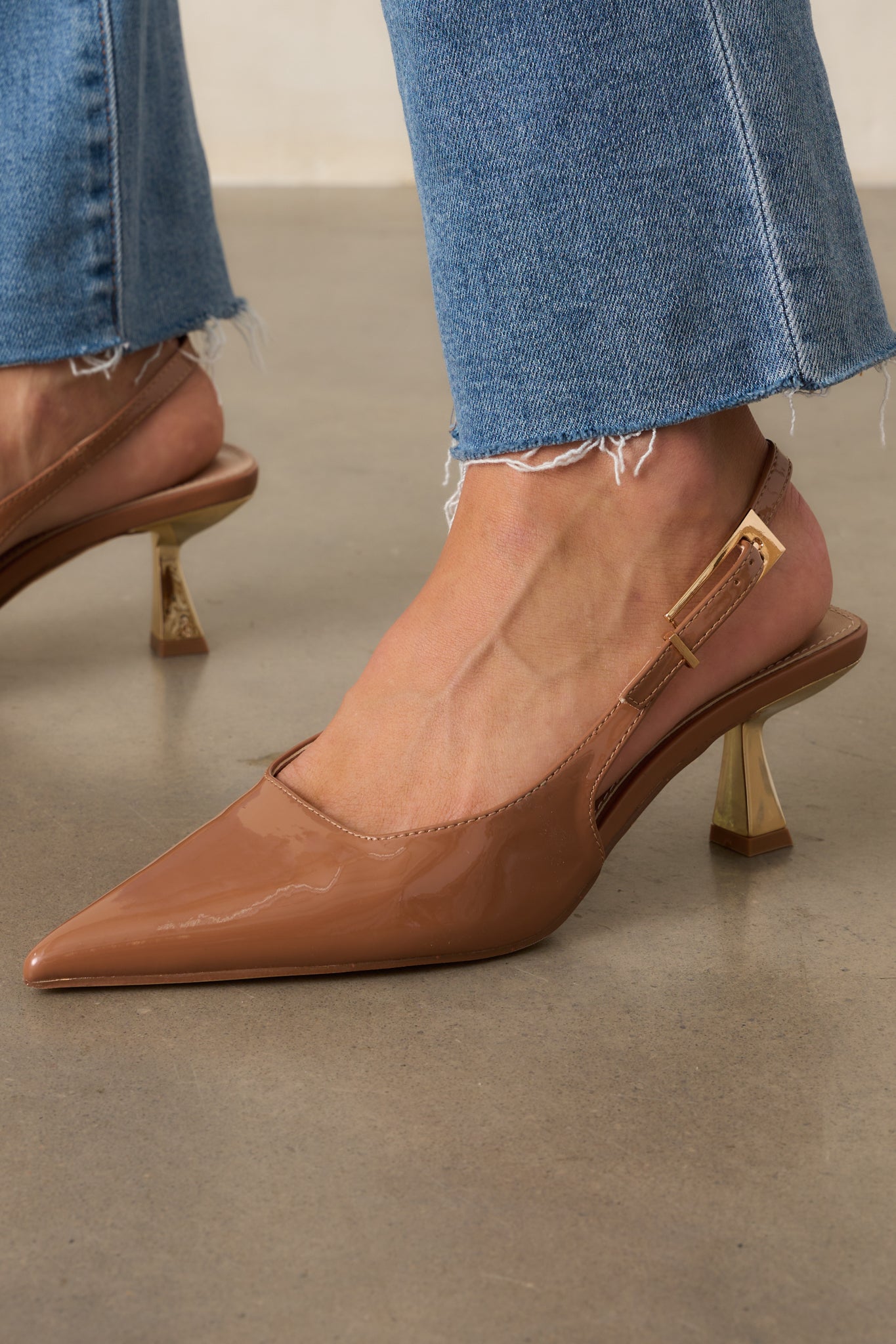 Cropped angle of the brown heels emphasizing the gold kitten heel and pointed toe.