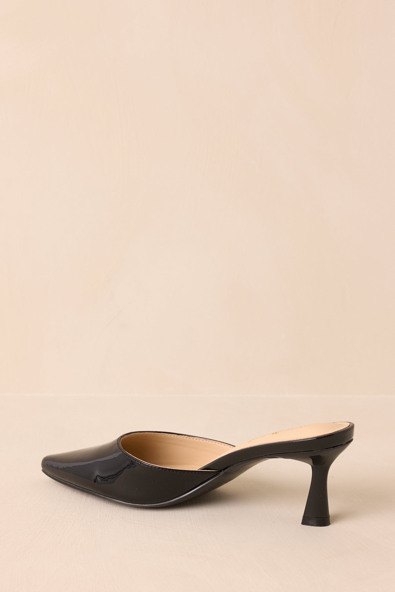 An angled back view of the black mule, highlighting the flared stiletto kitten heel and slip-on construction.