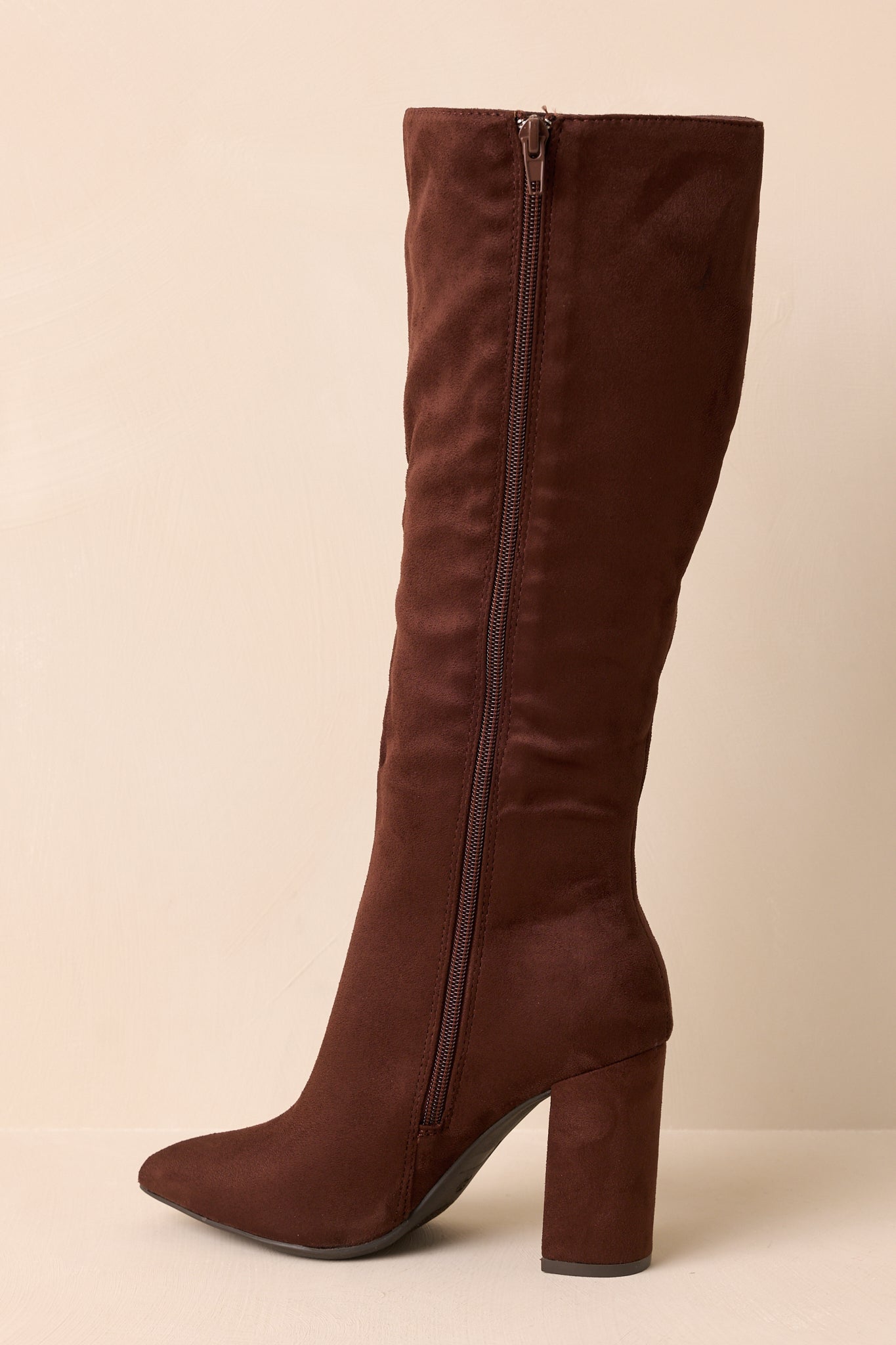 Angled back view of dark brown knee-high boots showing slouched shaft and block heel structure.
