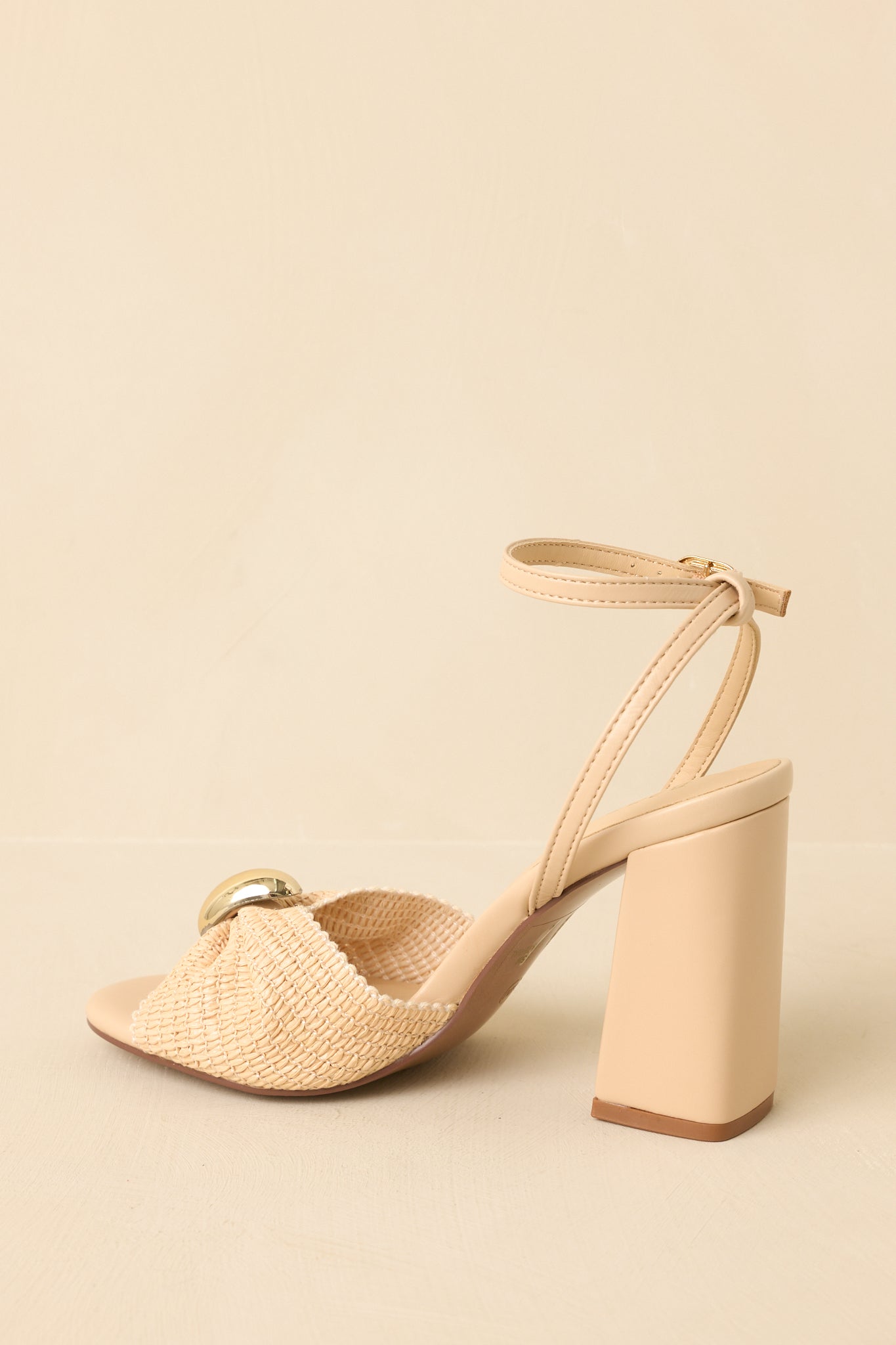 Angled back view showing the block heel, ankle strap, and woven detailing of the sandals.