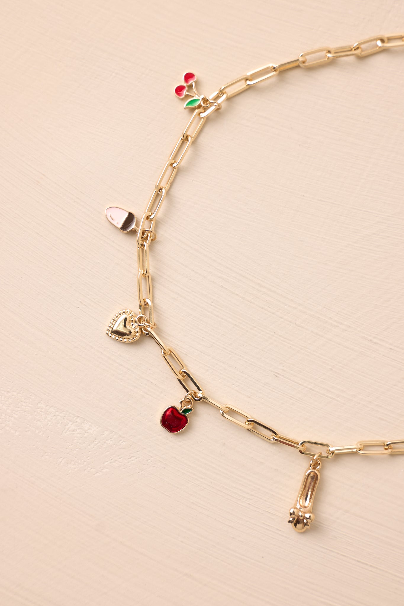 Angled cropped view highlighting the arrangement of multiple small gold charms along the rectangular chain.