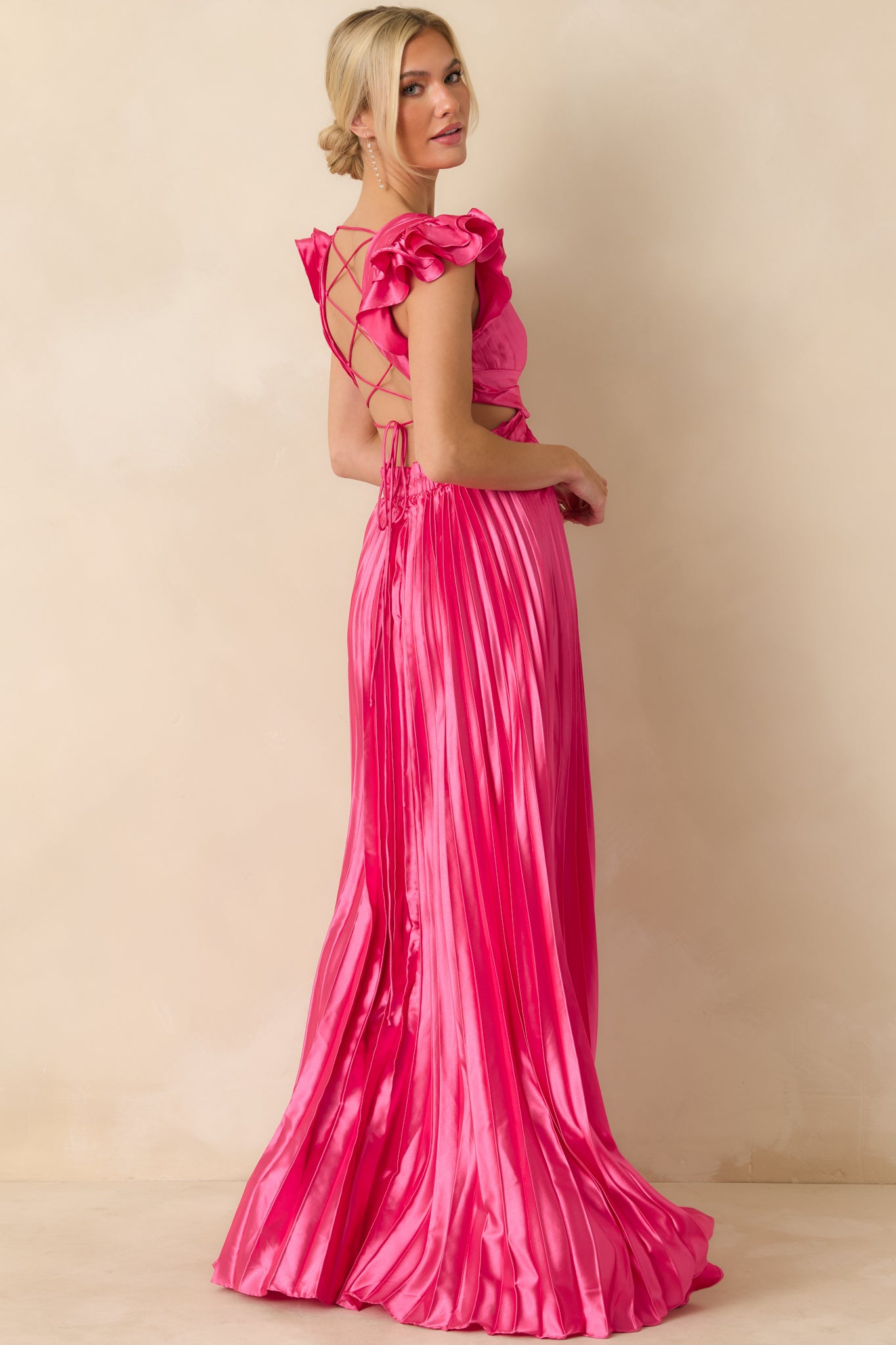 Slightly angled front view highlighting adjustable fit at sides, ruffled sleeves, and flowing pleated fabric.