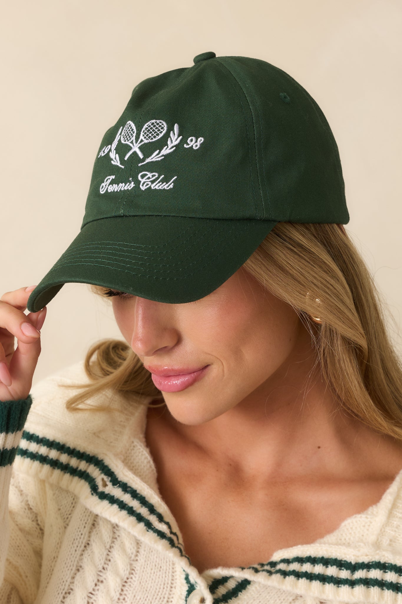 Angled front view showing curved brim and embroidered tennis motif on the cap.