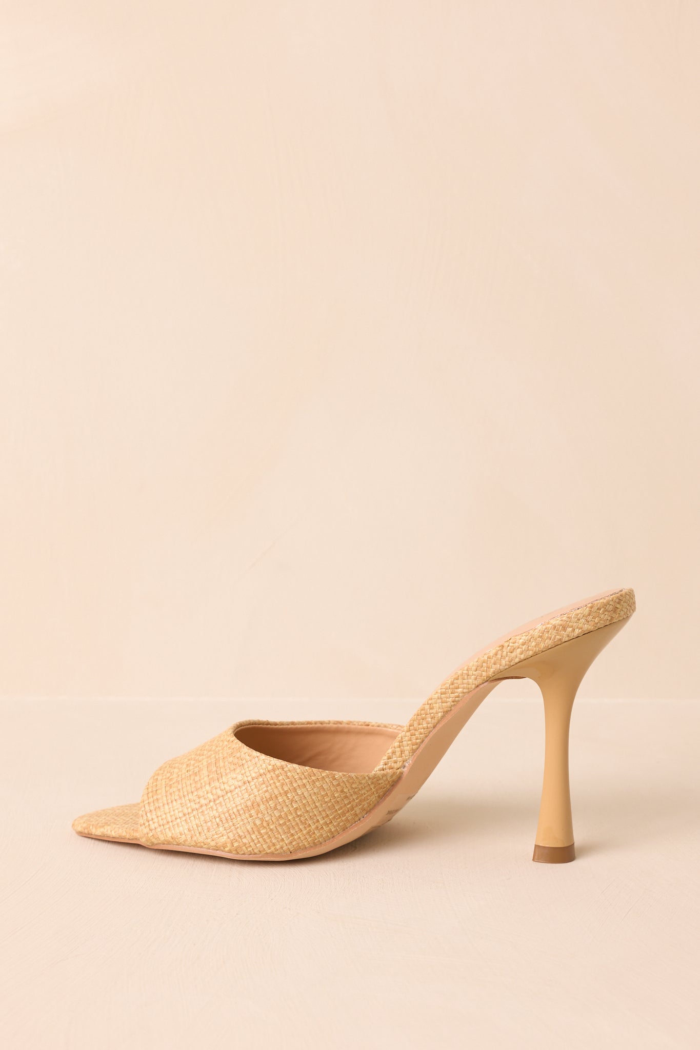 An angled shot from the side and back, showing the heel curve and raffia texture.