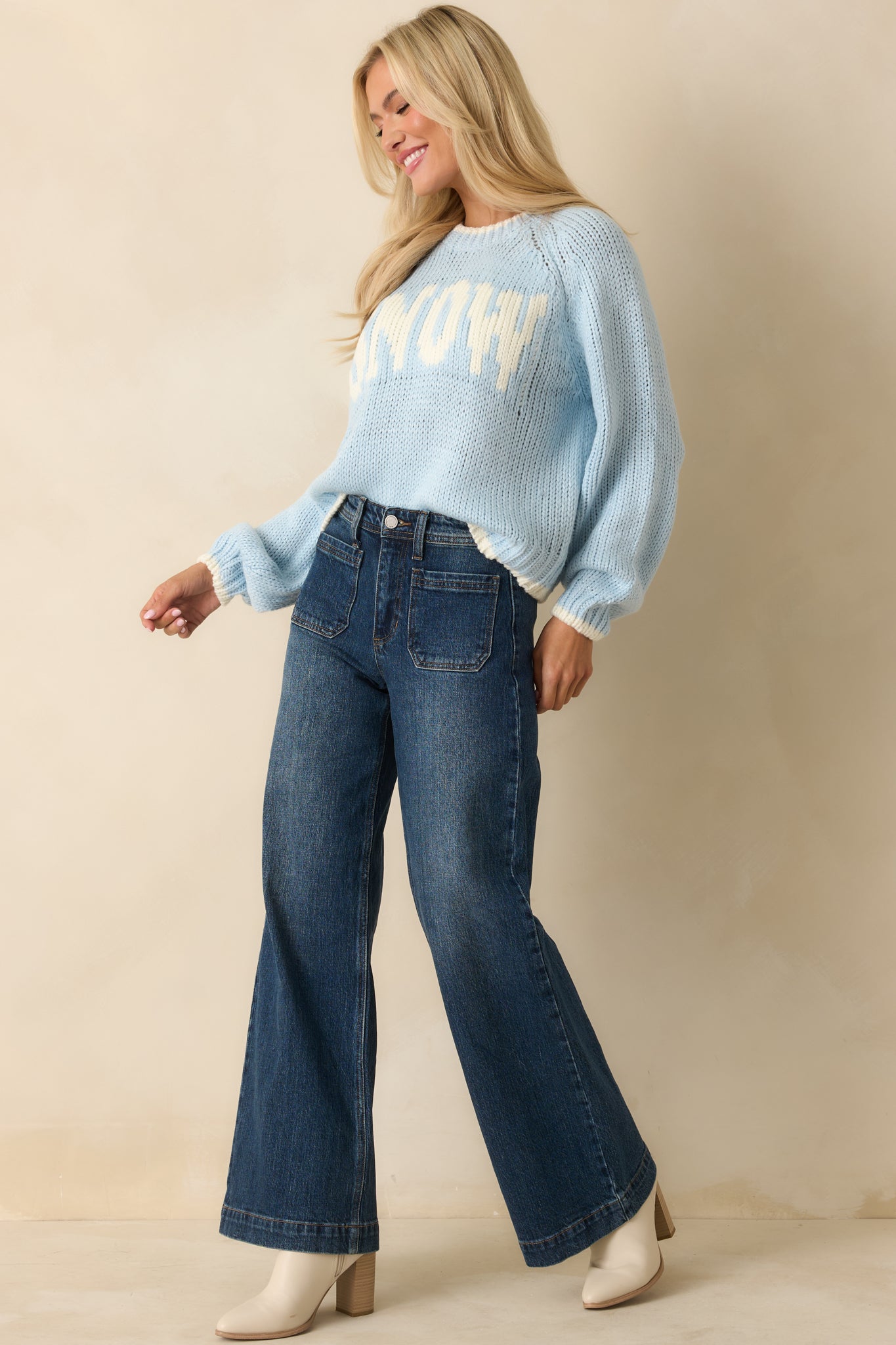 Angled side view showcasing the full length of the sweater with ribbed cuffs, hem, and clean graphic placement.