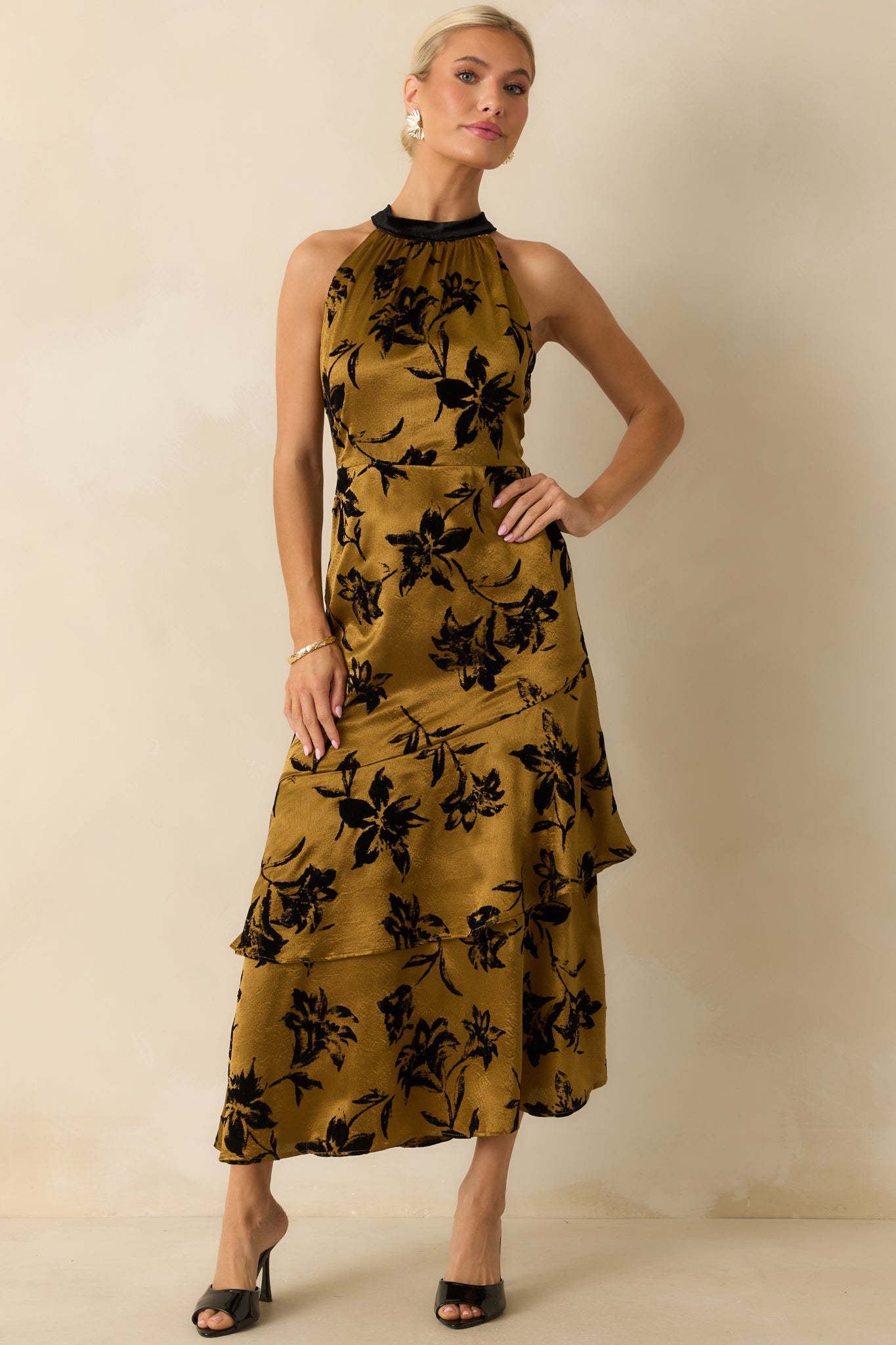 Slight angled view of the dark gold floral satin midi dress highlighting the fitted bodice and flowing satin texture.