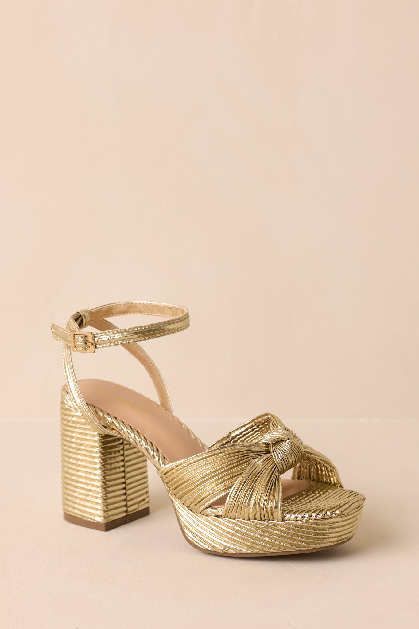An angled view emphasizing the metallic gold finish and platform silhouette.