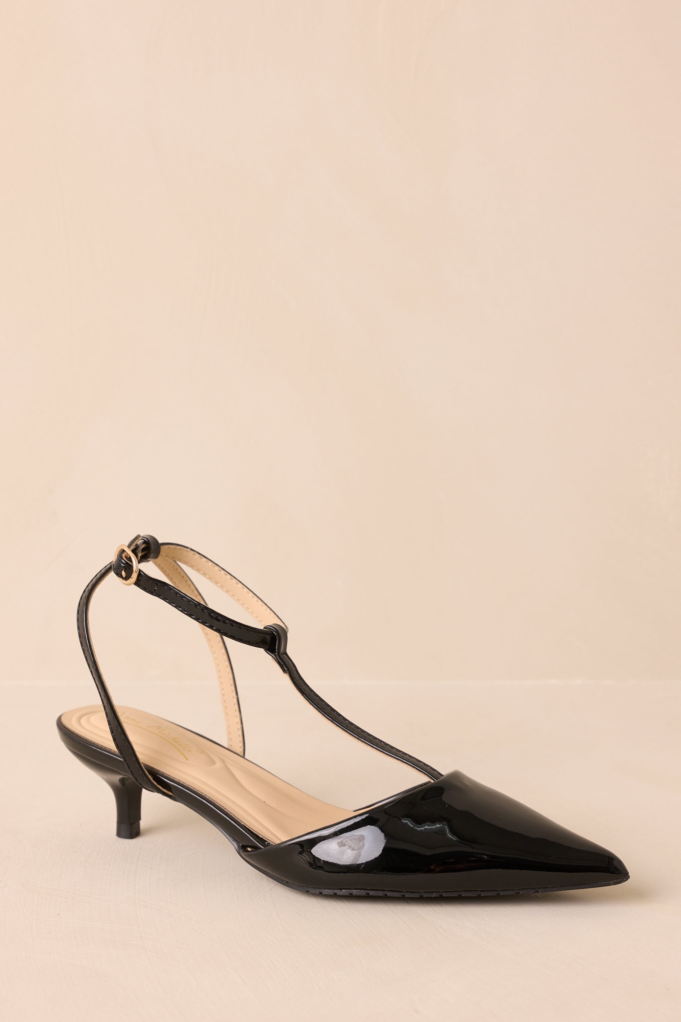Angled view highlighting pointed toes and shiny patent finish of black heels.