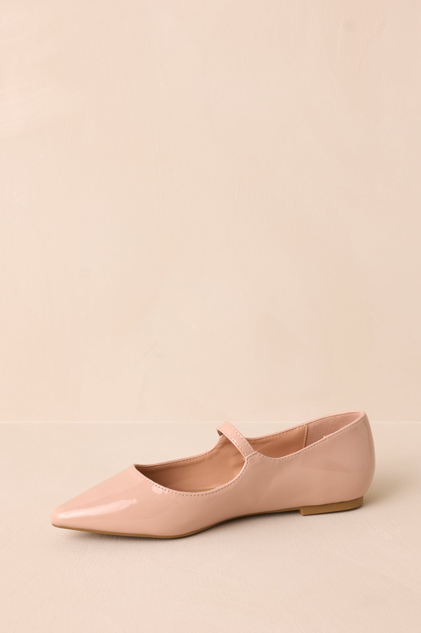 Angled view of beige flats highlighting the pointed toe, sleek material, and the elegant buckle across the foot strap