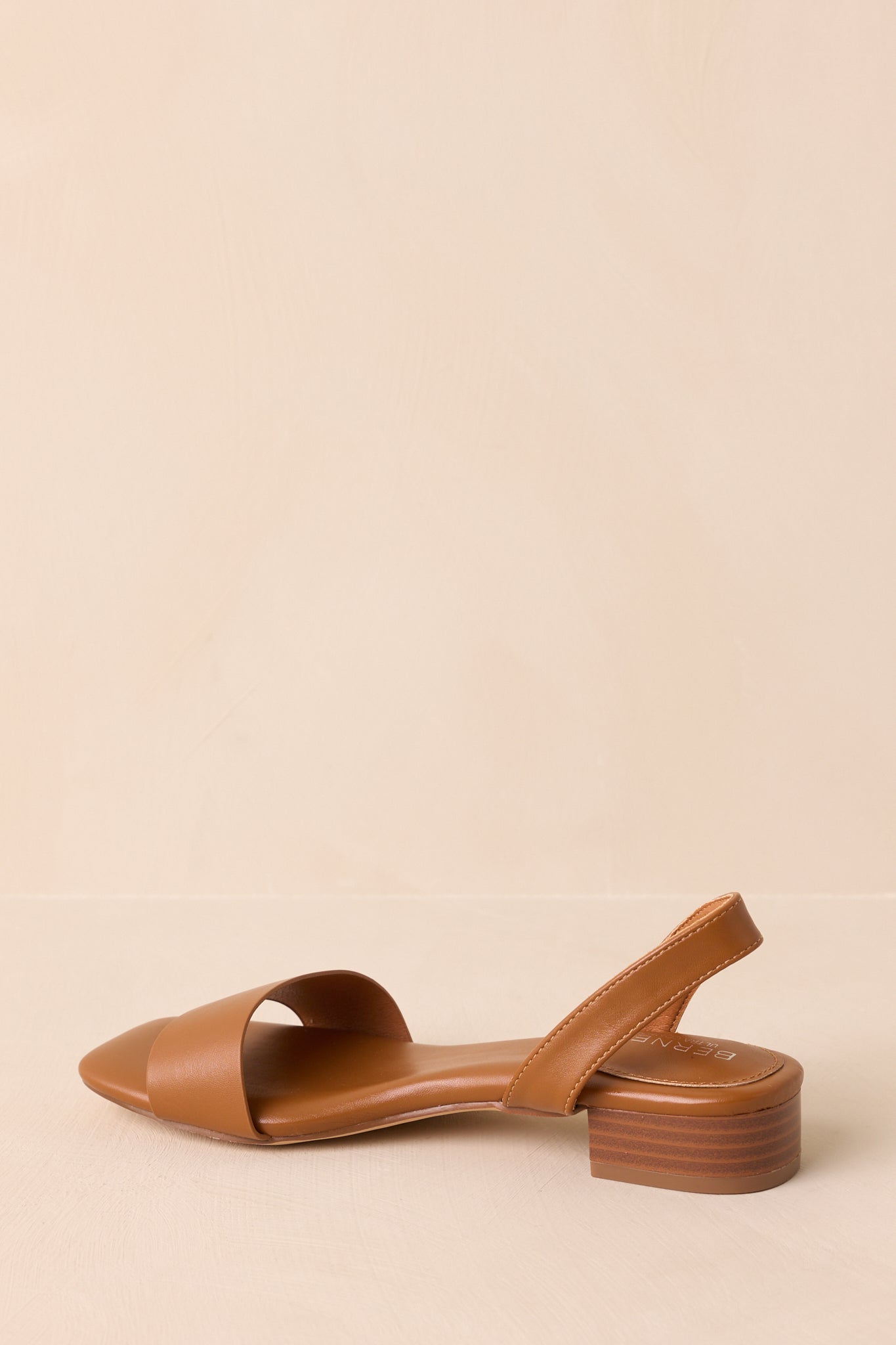 Angled view showing caramel brown faux leather texture and strap placement.