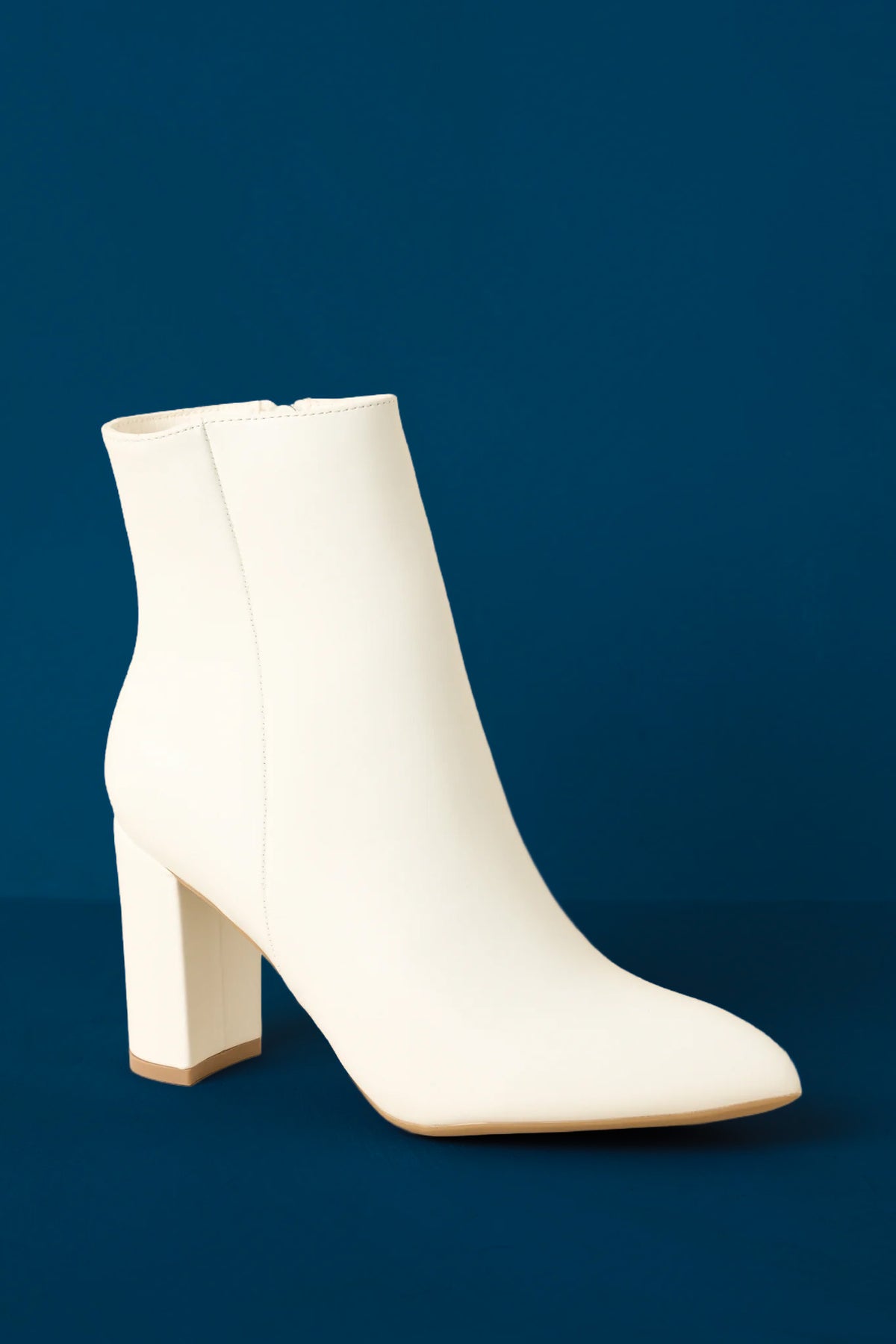 Ankle boots shown from a low angle emphasizing the block heel and structured shape on blue background.