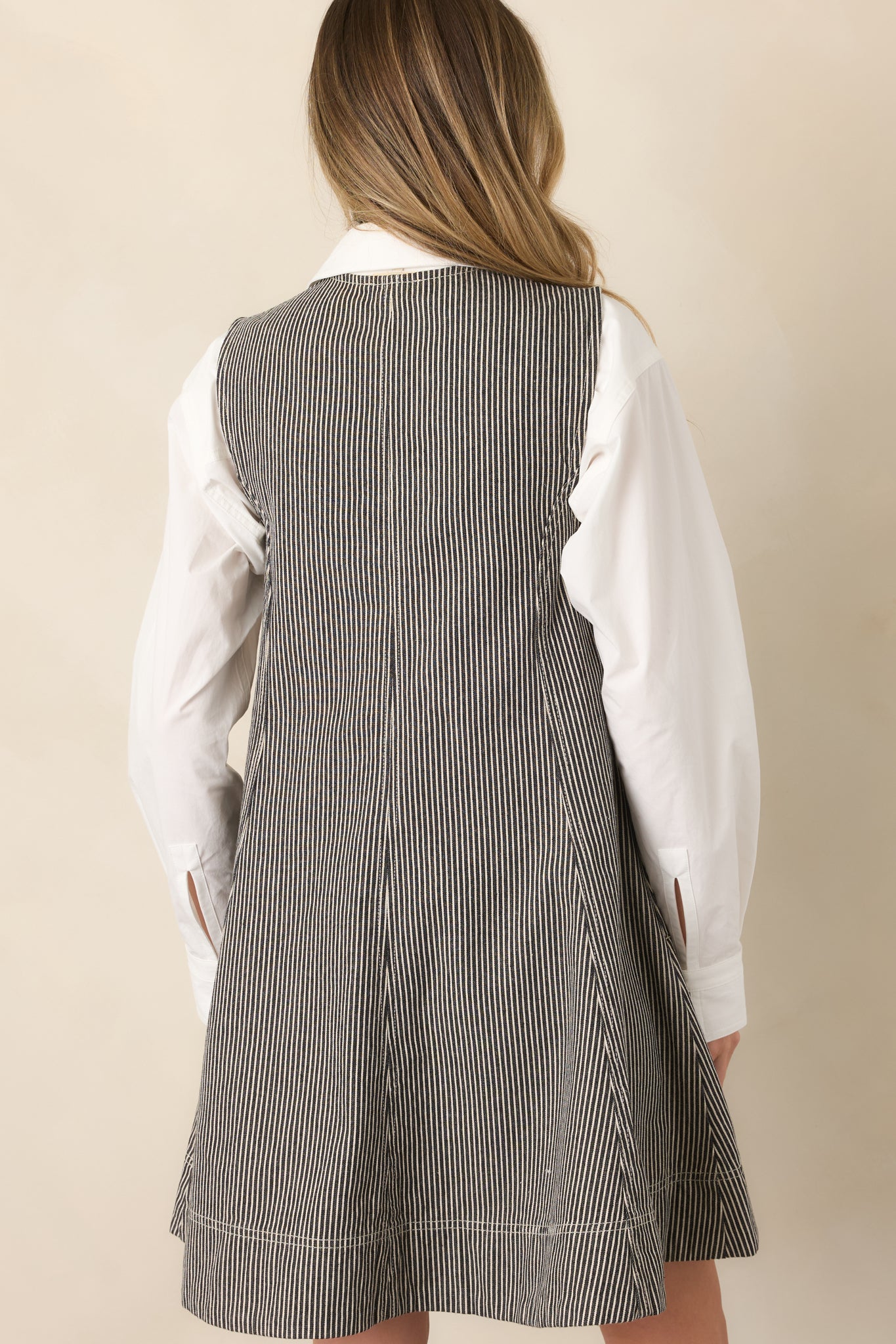 Rear view of the anthracite grey and ivory striped mini dress showing its sleeveless cut, angled seams, and flared hem.