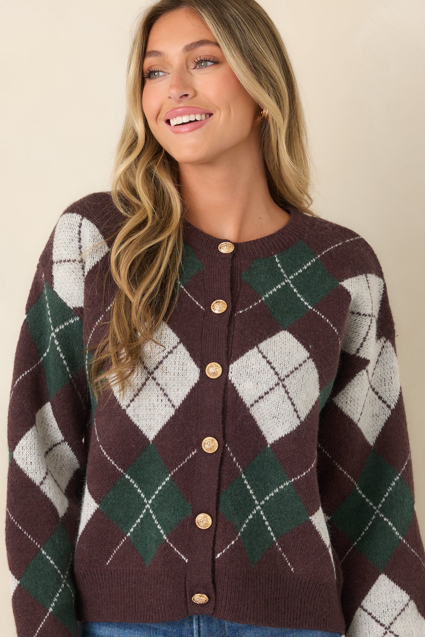 Close view of the argyle cardigan highlighting the gold-tone button closure, round neckline, and classic knit pattern.